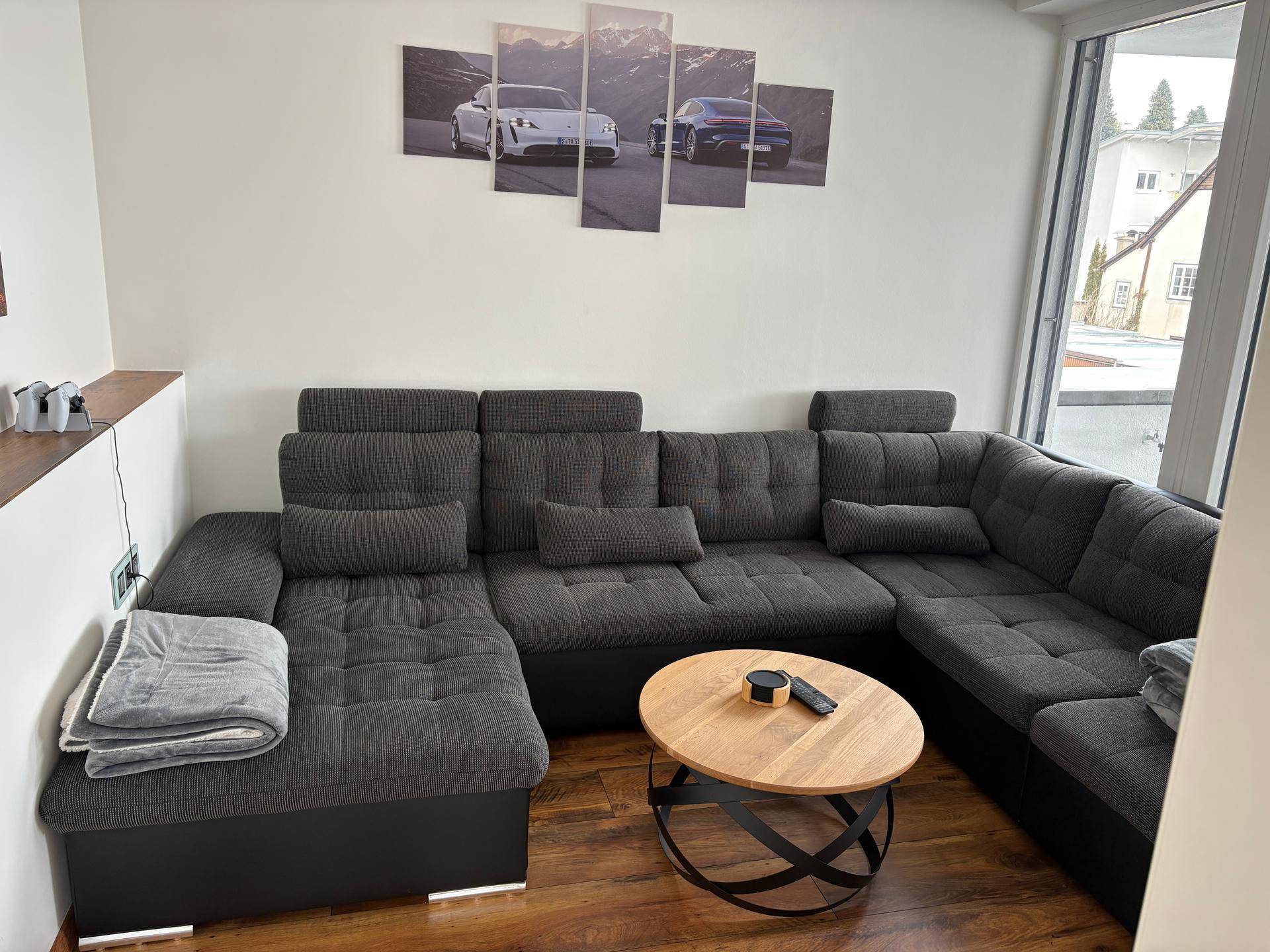 Moderner Wohnbereich mit großem Ecksofa, Holztisch und stilvoller Wanddekoration auf Holzboden.