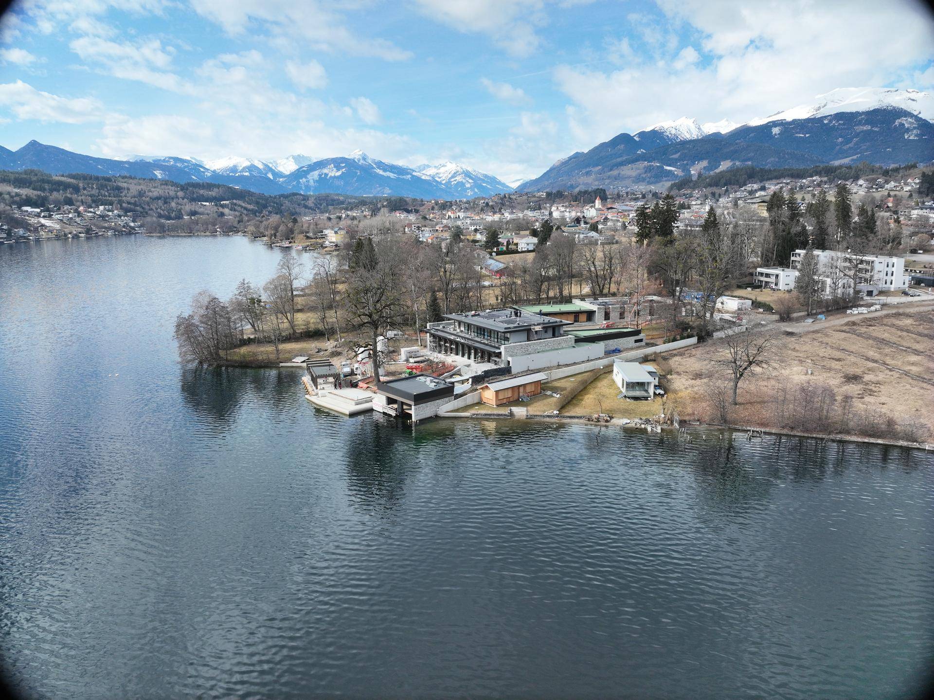 Moderne Architektur am Seeufer mit weitläufigem Blick auf den See und die umliegenden Berge.