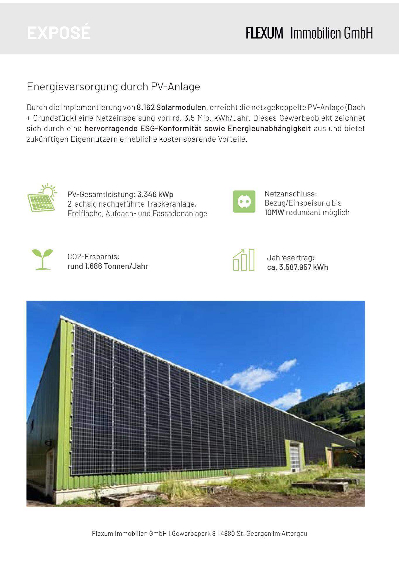 Seitenansicht der Industriehalle mit Photovoltaikmodulen an der Fassade und einem grünen Berghang im Hintergrund.
