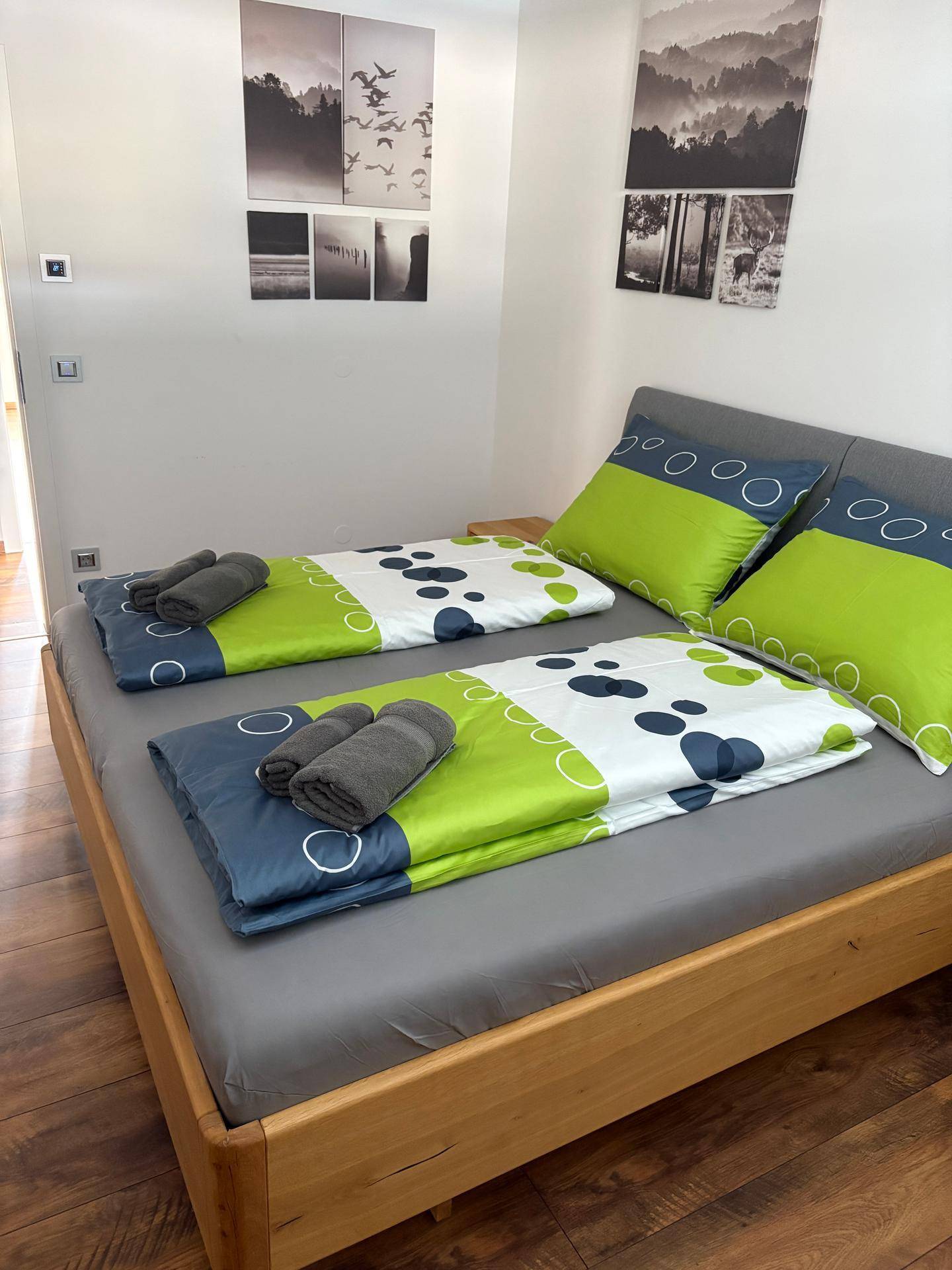 Gemütliches Schlafzimmer mit Holzbett, Nachttischen und dekorativen Bildern, die eine ruhige Atmosphäre schaffen.