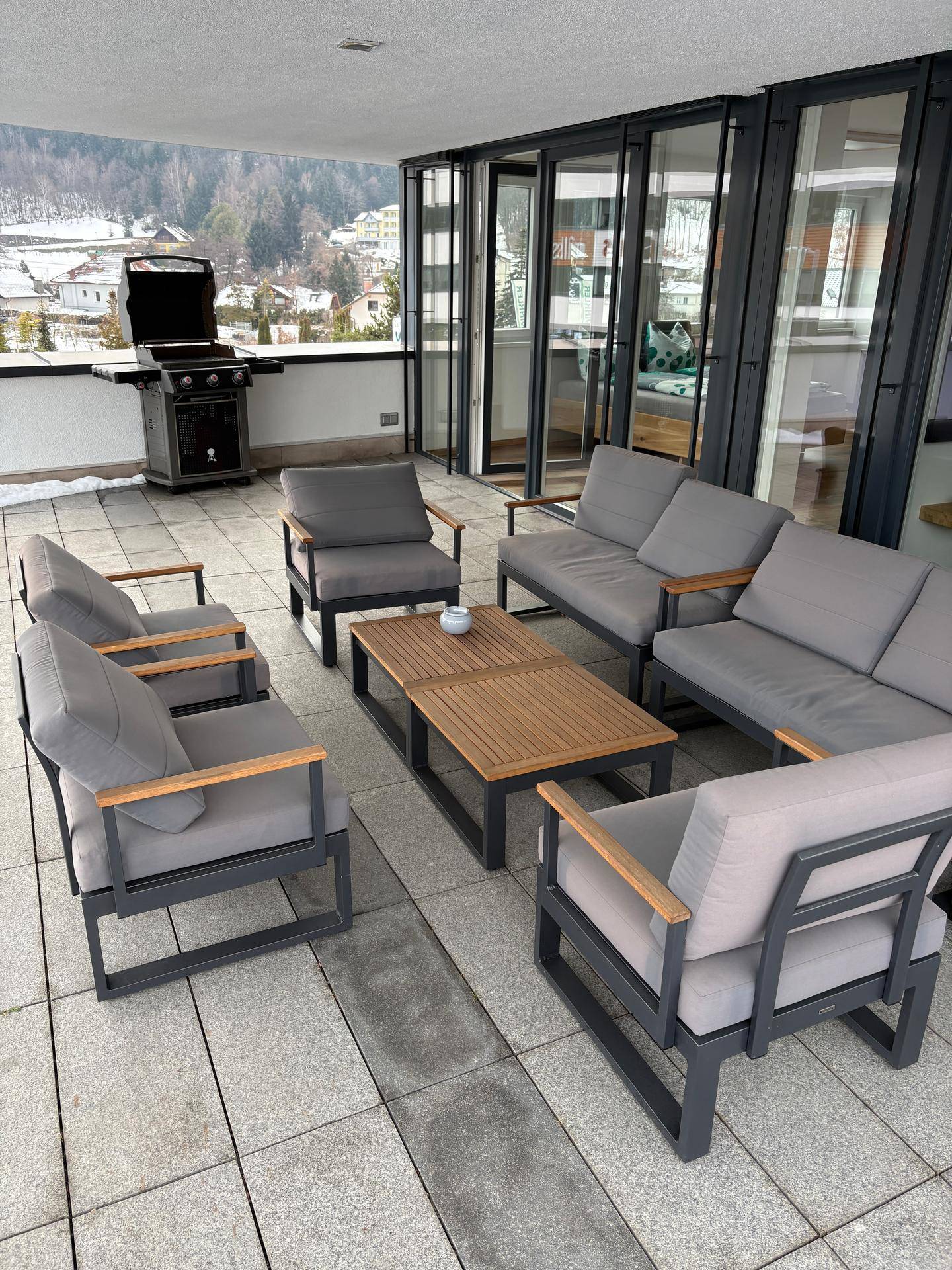 Große Terrasse mit bequemen Outdoor-Sitzgelegenheiten, Holztisch und einem Grill für gesellige Abende.