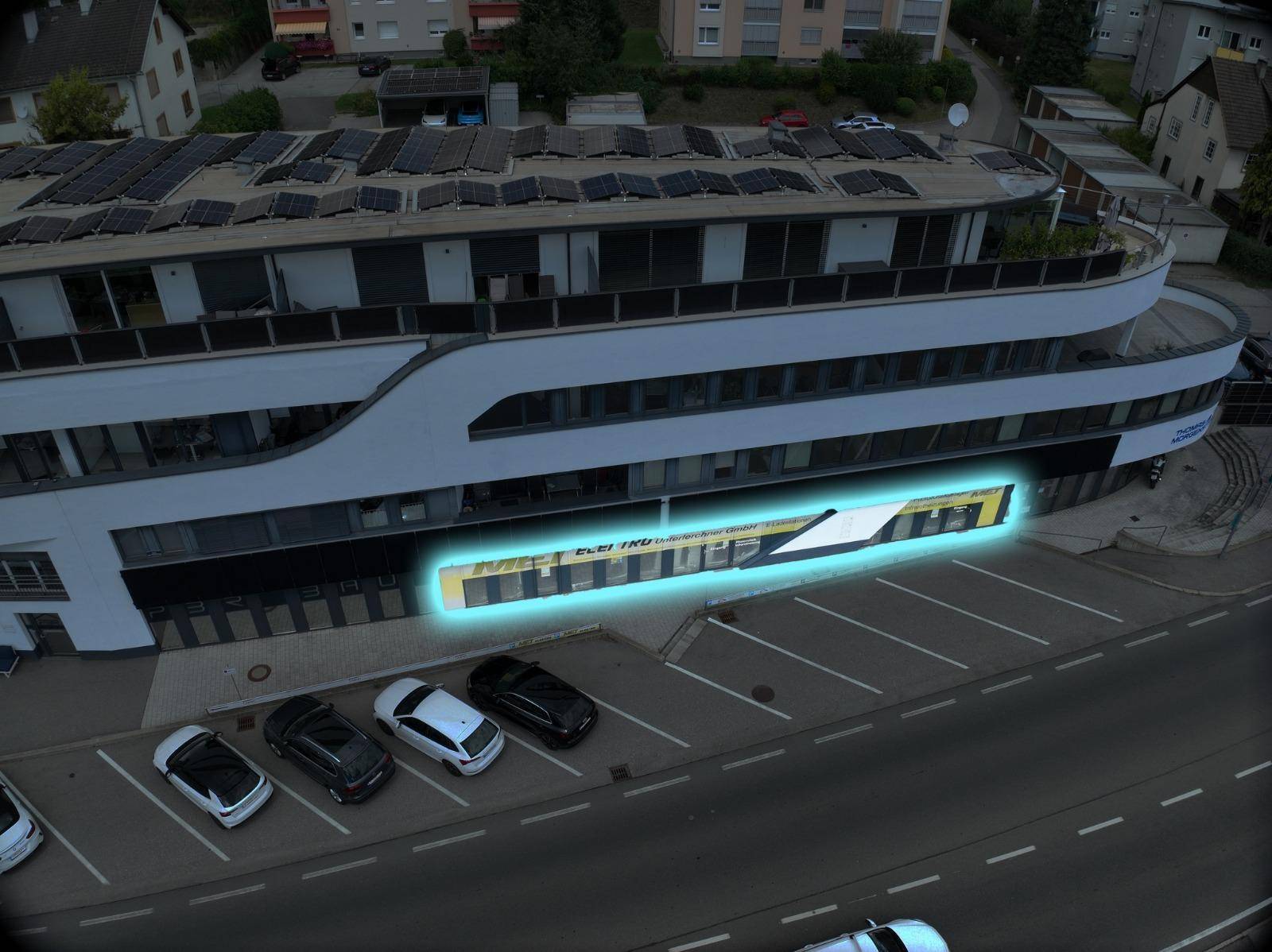 Luftaufnahme der modernen Gewerbeimmobilie mit Solaranlage auf dem Dach und Parkplätzen.