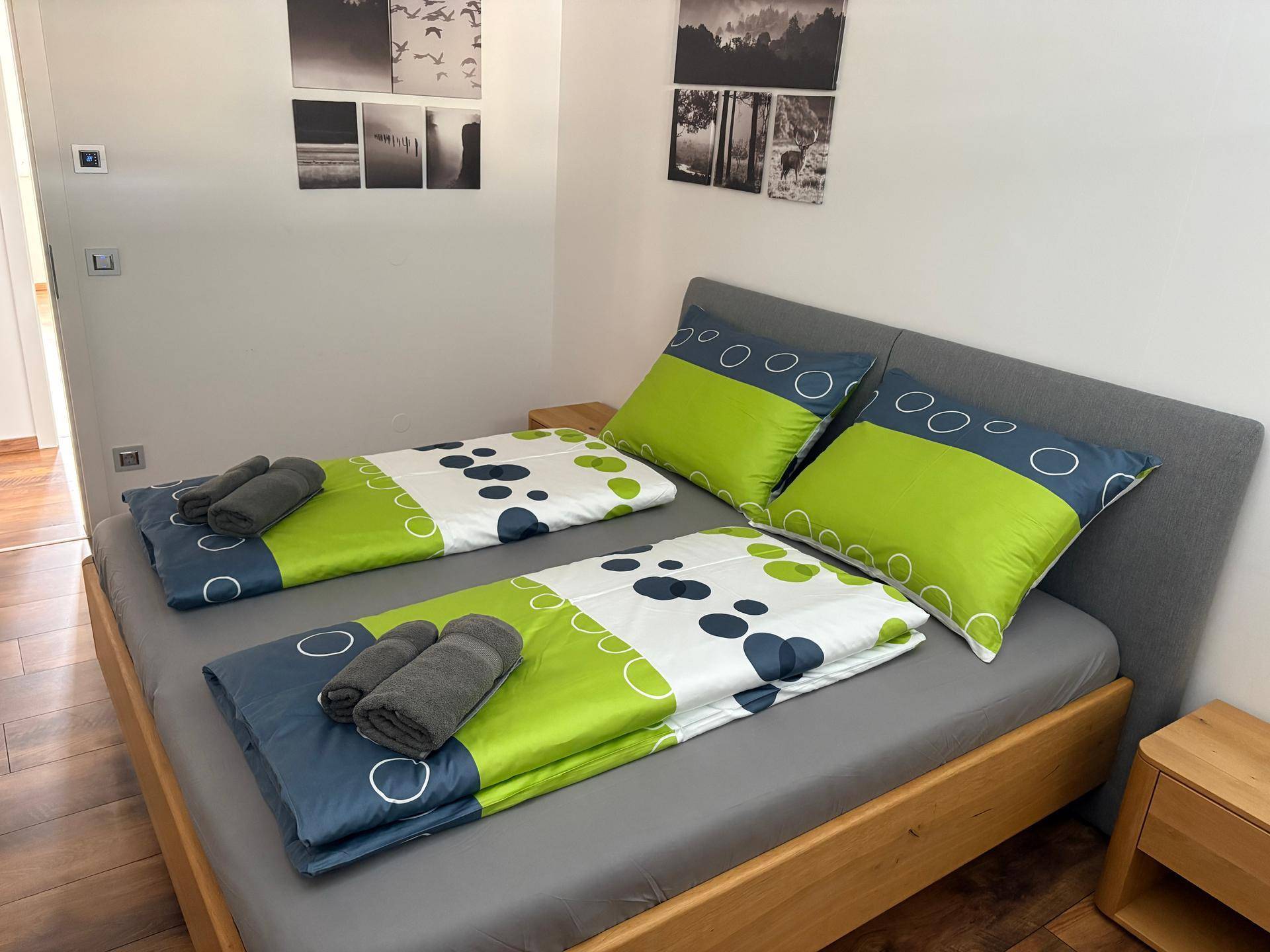 Helles Schlafzimmer mit Holzbett, passenden Nachttischen und stilvollen Schwarz-Weiß-Bildern an der Wand.