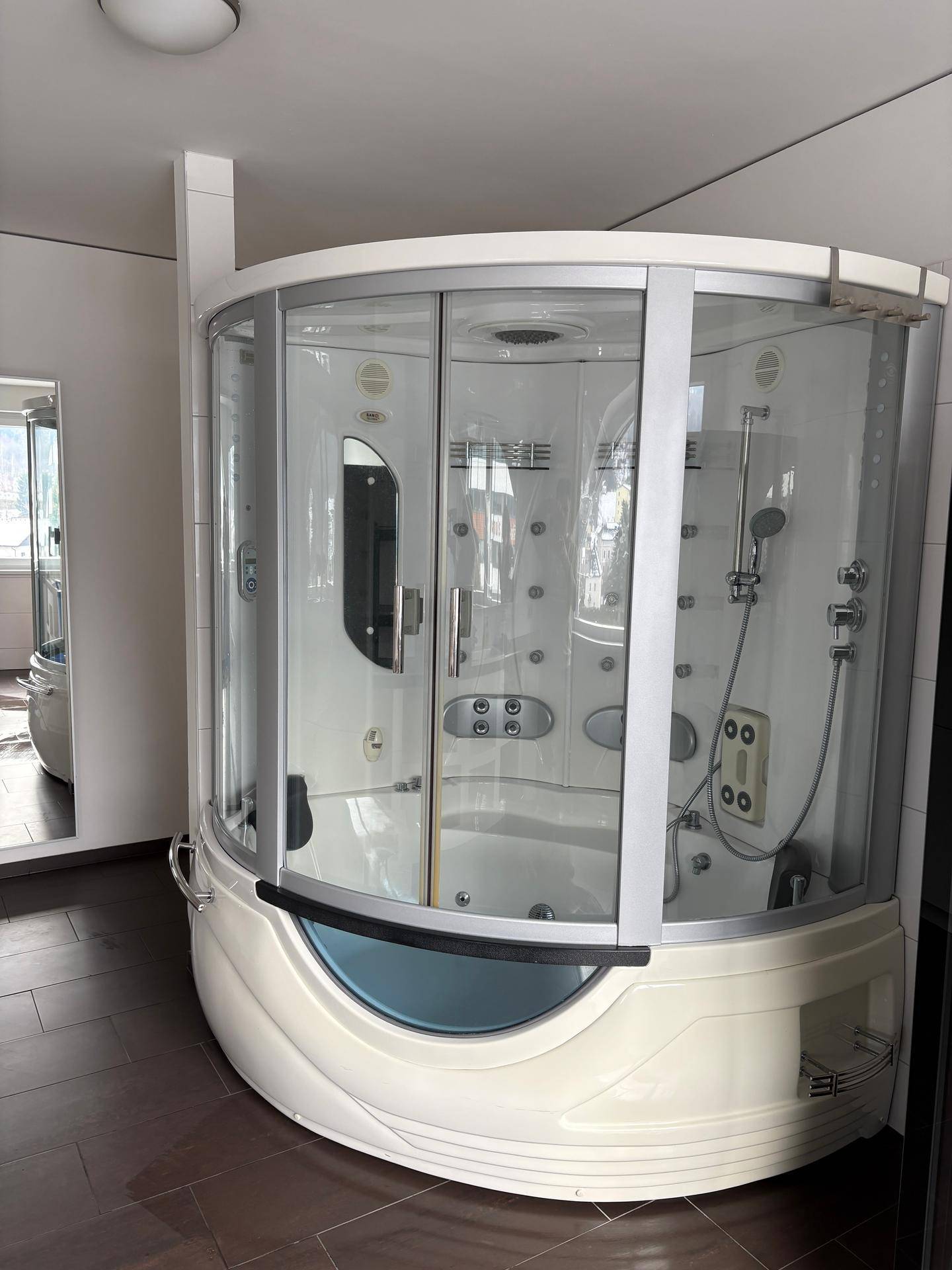 Modernes Badezimmer mit einer geräumigen Duschkabine, ausgestattet mit Massagedüsen und Sitzgelegenheit.