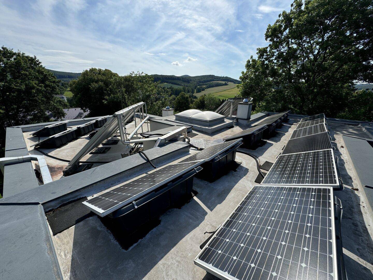 Dachfläche mit installierten Photovoltaik-Modulen und weitem Blick über die Landschaft.