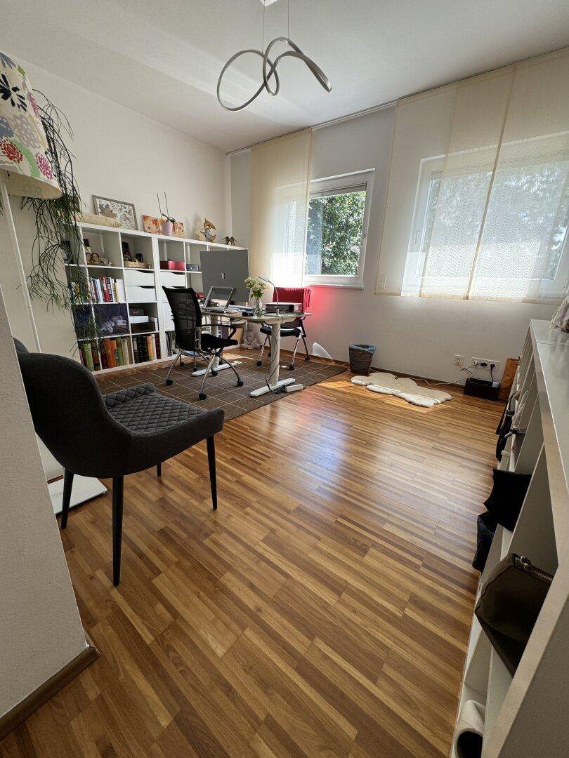 Geräumiges Arbeitszimmer mit Holzboden, Regalen und viel Tageslicht durch die Fenster.