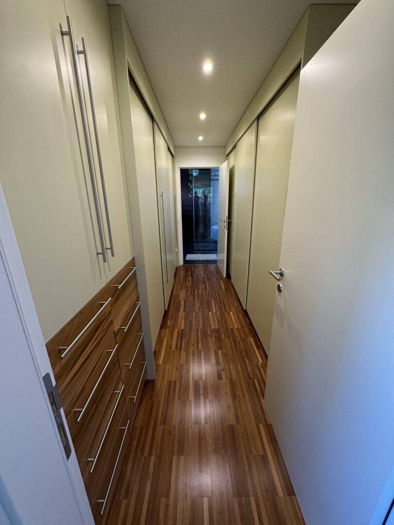 Langer Flur mit integrierten Schränken und Holzboden, ideal als Ankleidebereich.