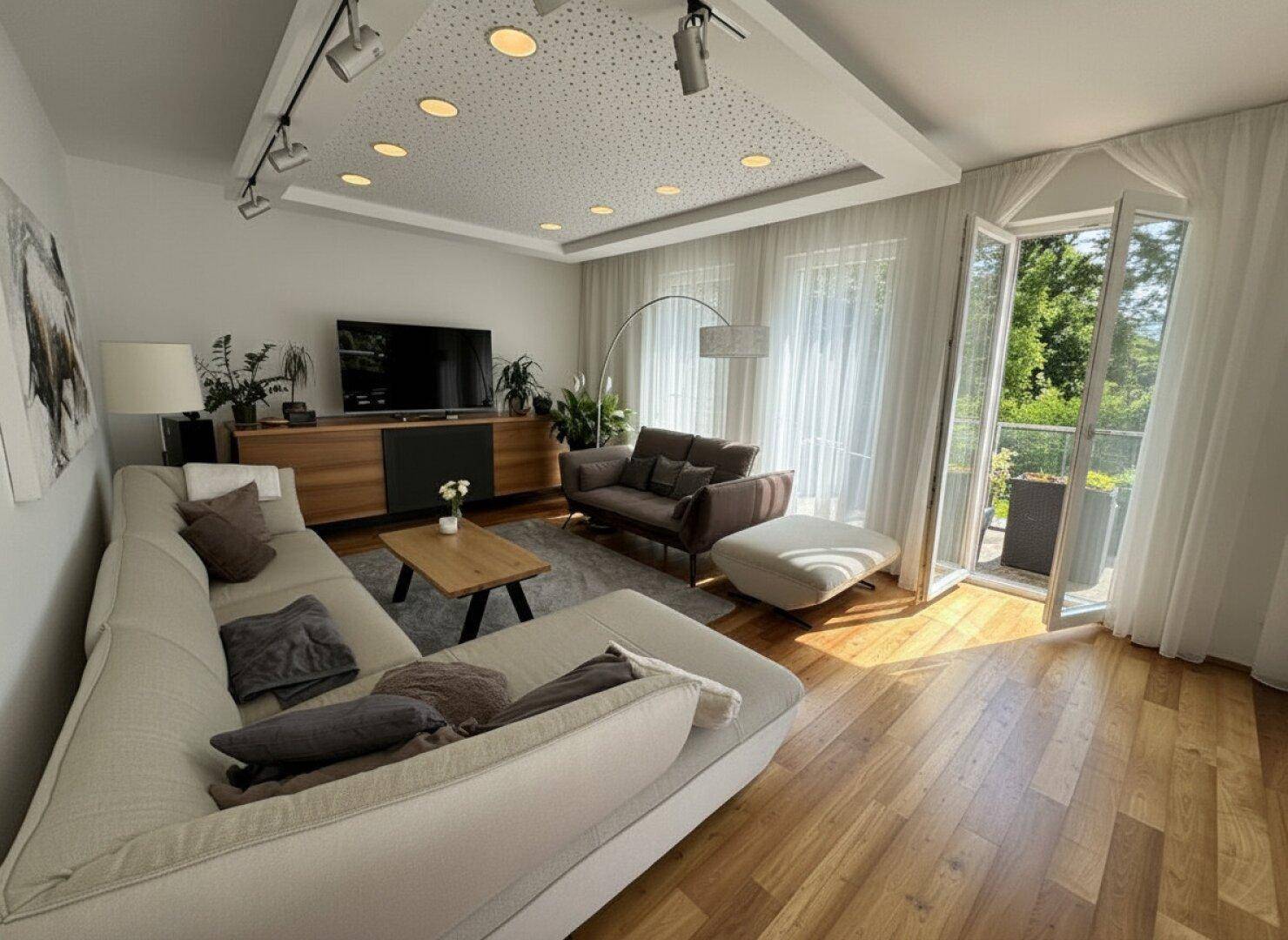 Modernes Wohnzimmer mit Holzboden, großem Sofa und Zugang zum Balkon mit viel Tageslicht.