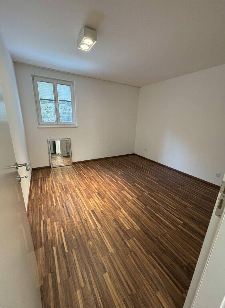 Leeres Schlafzimmer mit Holzboden und Fenster, bereit zur individuellen Gestaltung.