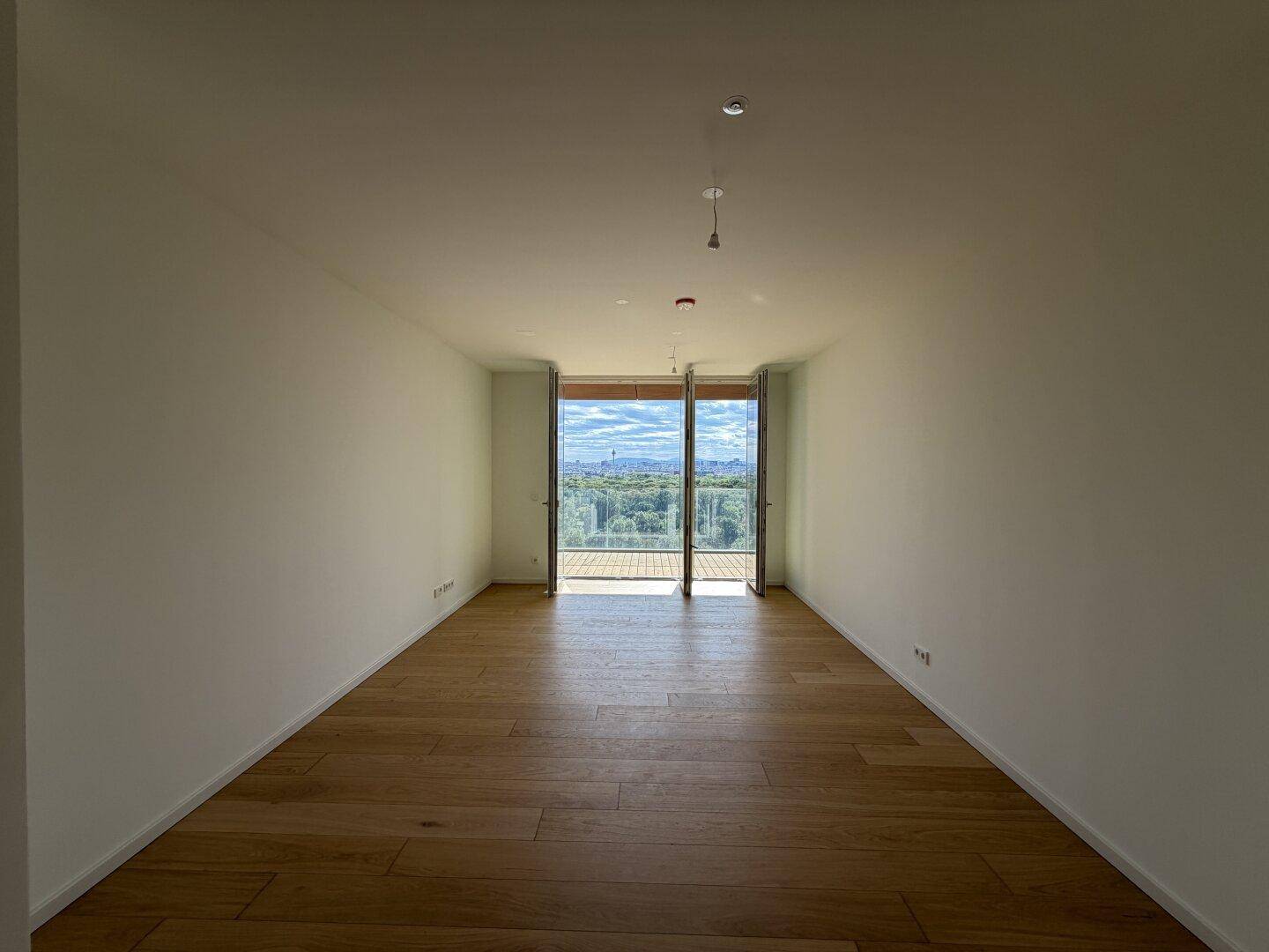 Moderner Wohnraum mit Eichenparkett und raumhohen Fenstern, die eine beeindruckende Aussicht bieten.