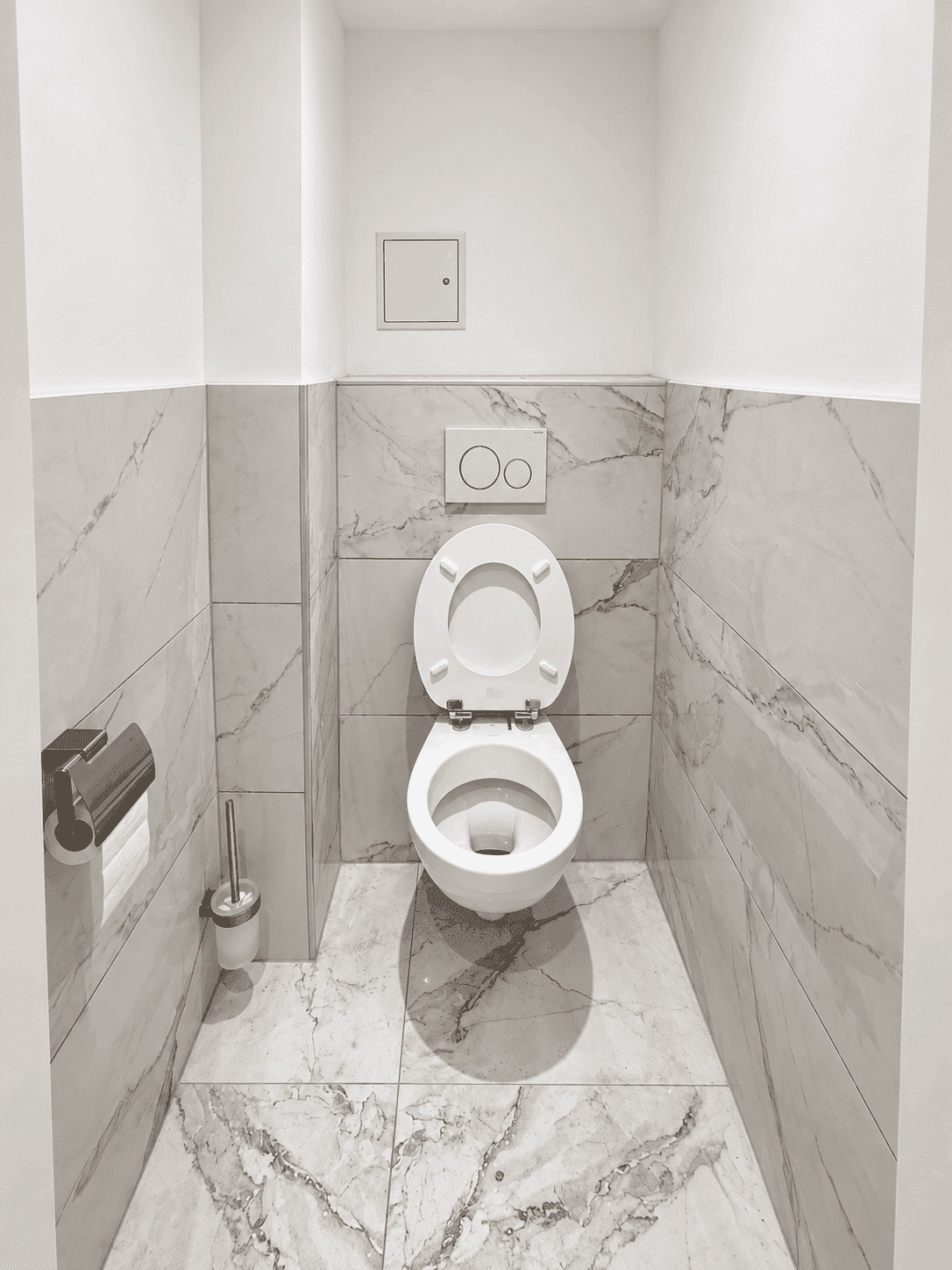 Separates WC mit wandmontierter Toilette und eleganten Marmorfliesen an Wänden und Boden, in einem minimalistischen Design.