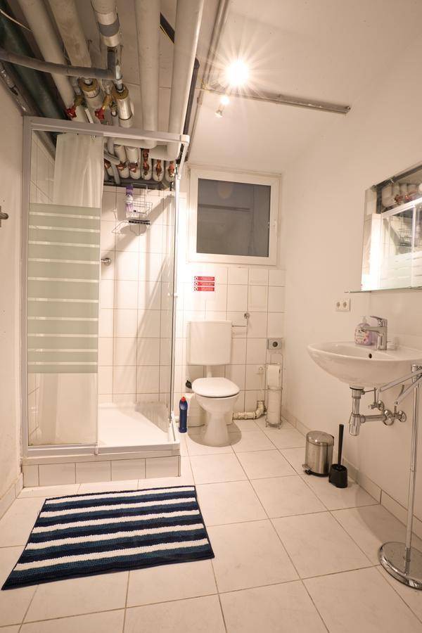 Helles Badezimmer mit Dusche, WC, Waschbecken und Fenster.