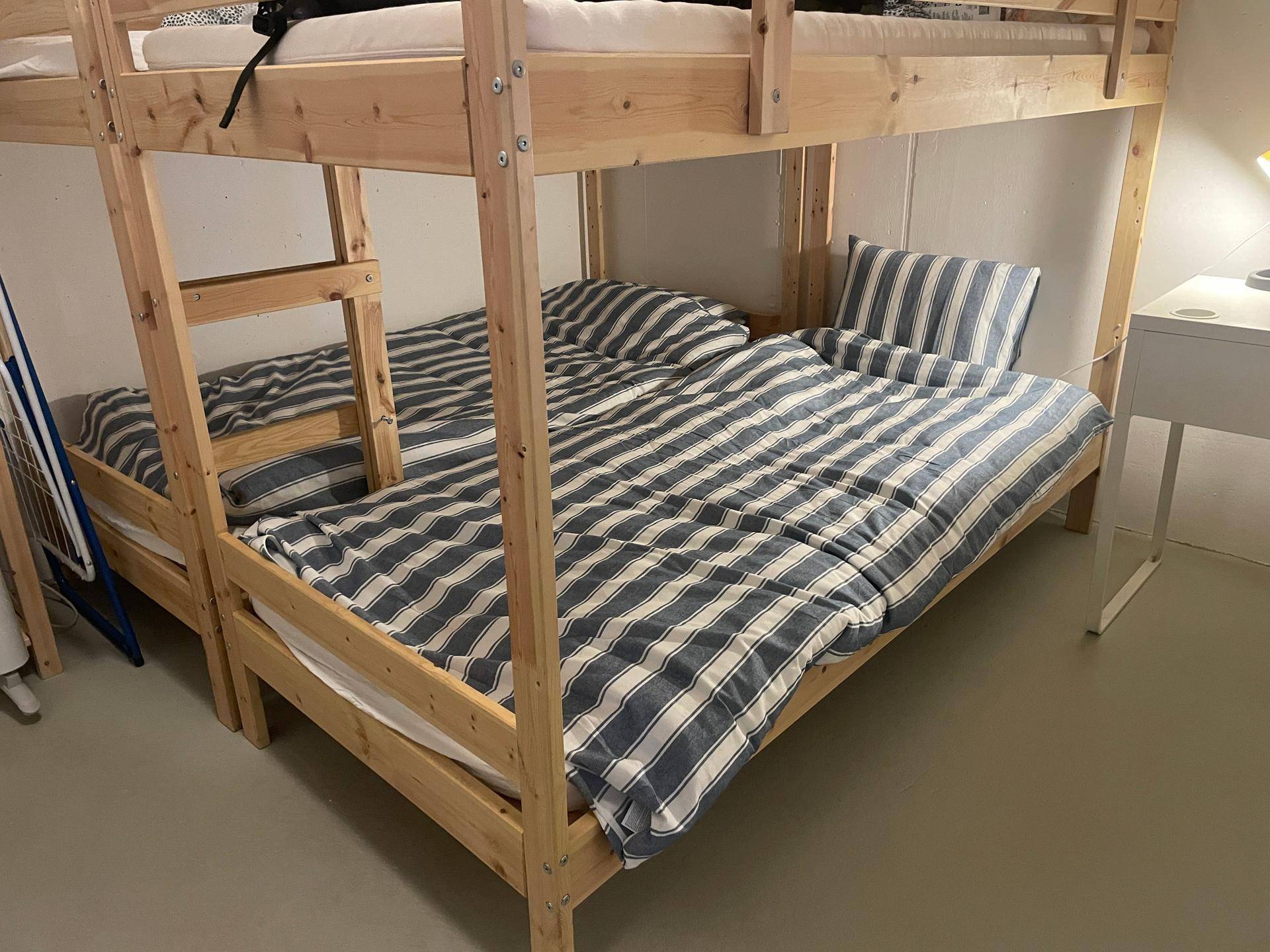 Schlafzimmer mit Etagenbetten und gestreiften Bettbezügen für mehrere Personen.