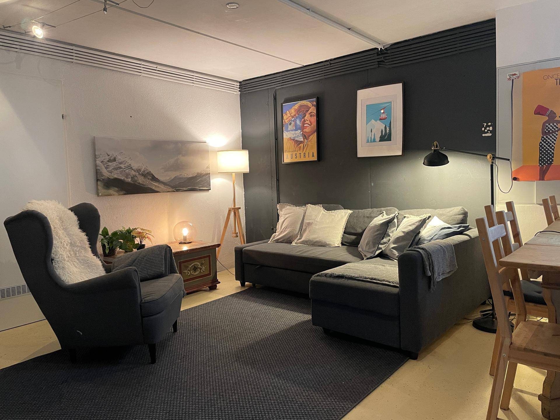 Gemütliche Sitzecke mit dunklem Sofa, Sessel und Stehlampe in modernem Ambiente.