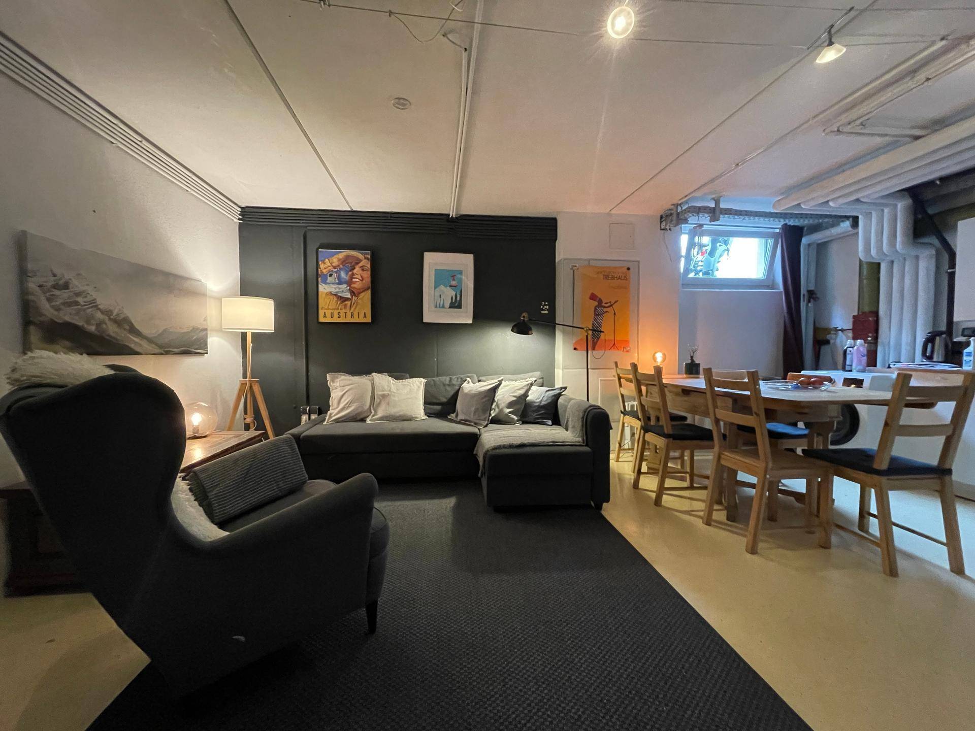 Heller Wohn- und Essbereich mit Holztisch, Sofa und dekorativem Teppich.