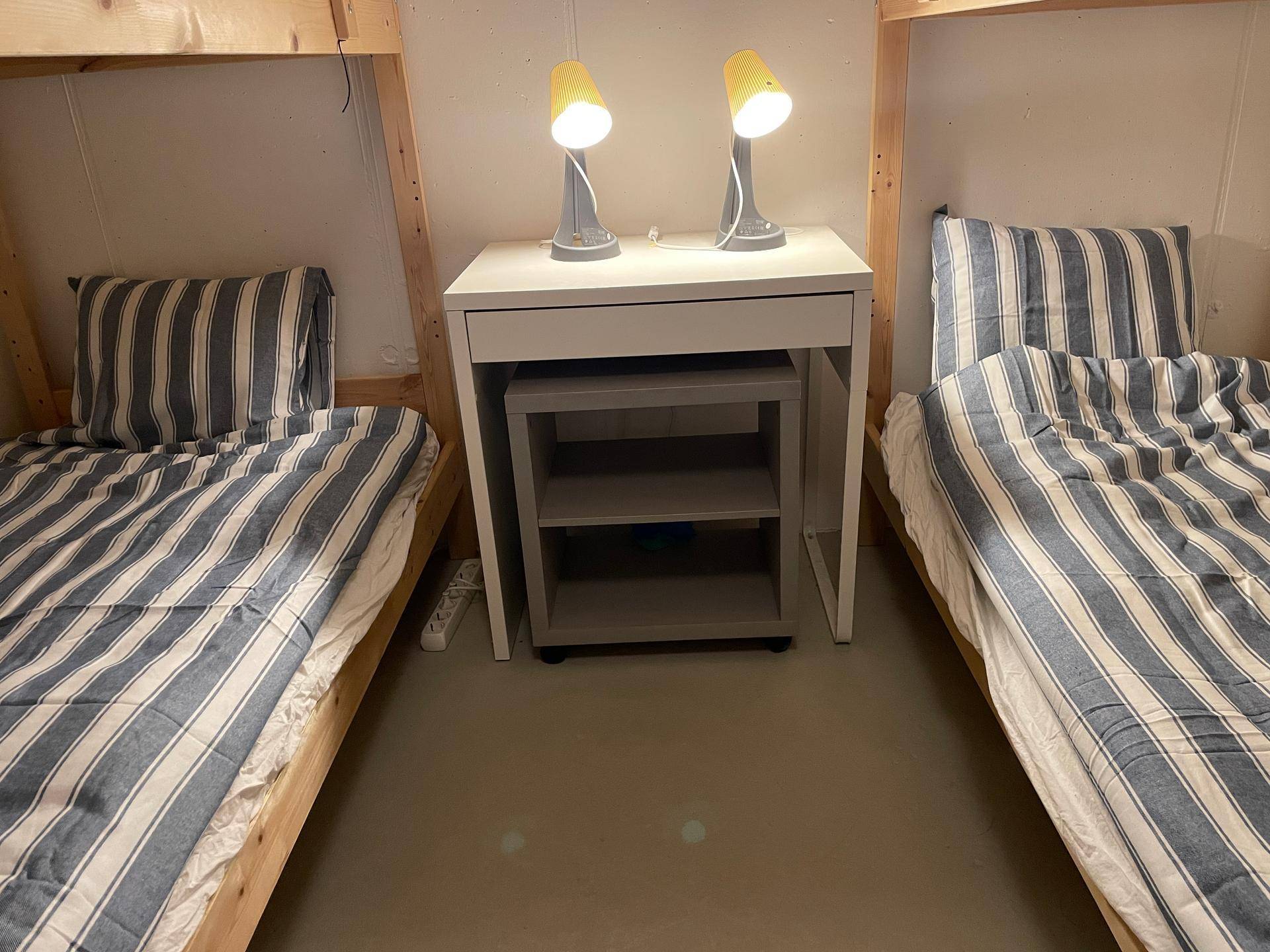 Zwischenraum der Etagenbetten mit Nachttisch und zwei Leselampen.