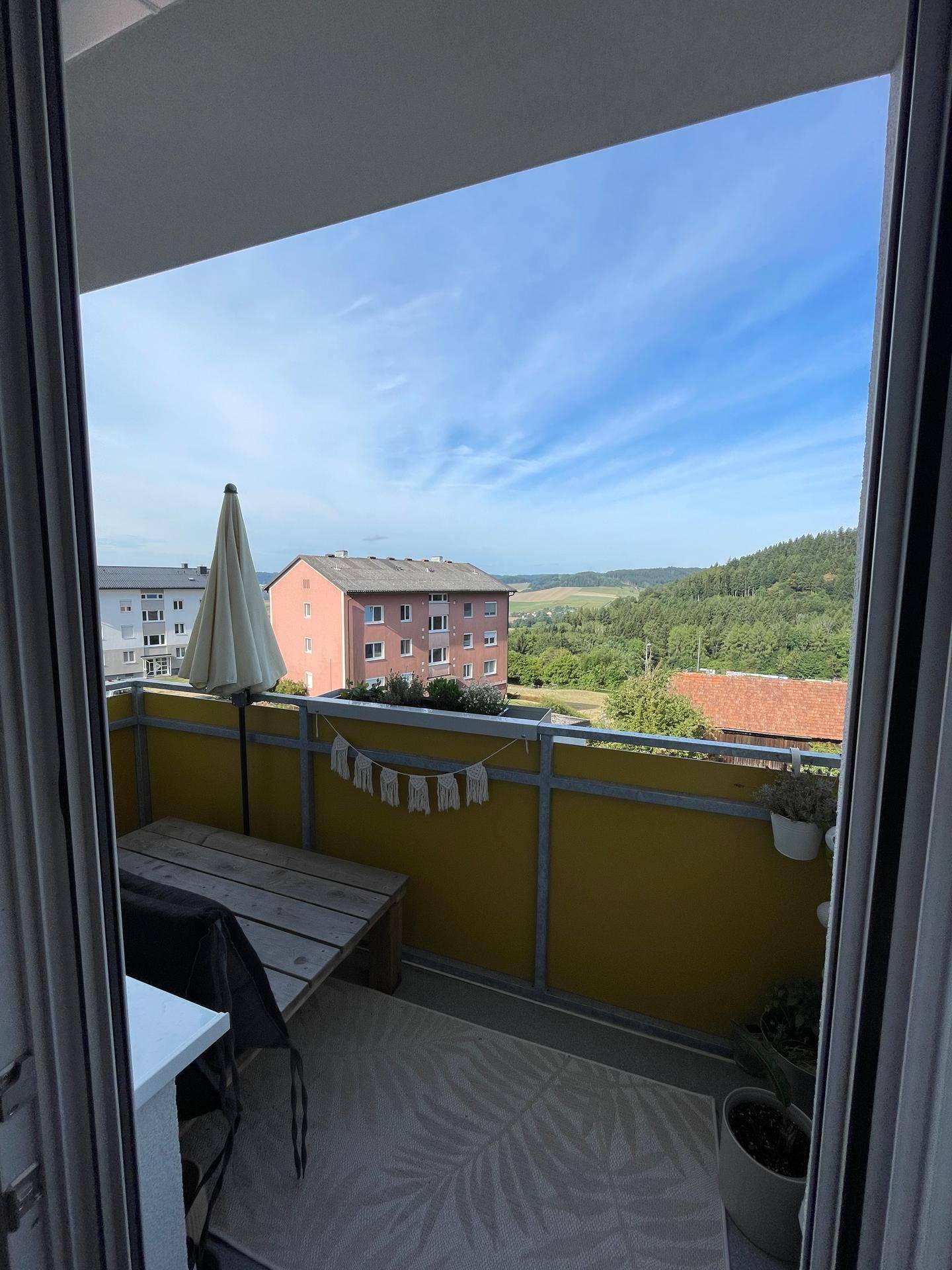 Sonniger Balkon mit Sitzgelegenheit und weitem Blick ins Grüne und auf die Umgebung.