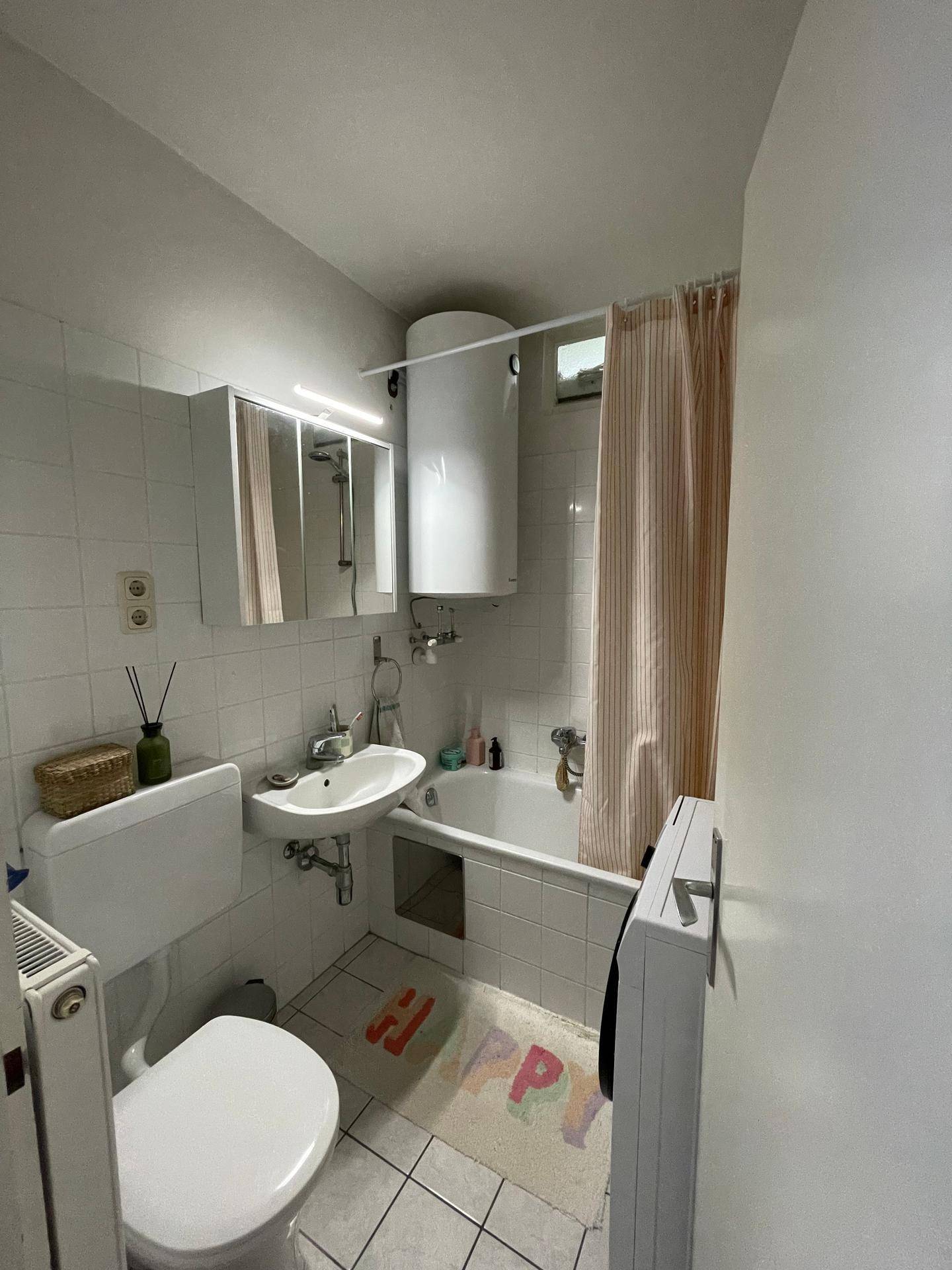 Badezimmer mit Badewanne, WC, Waschbecken und Spiegelschrank.