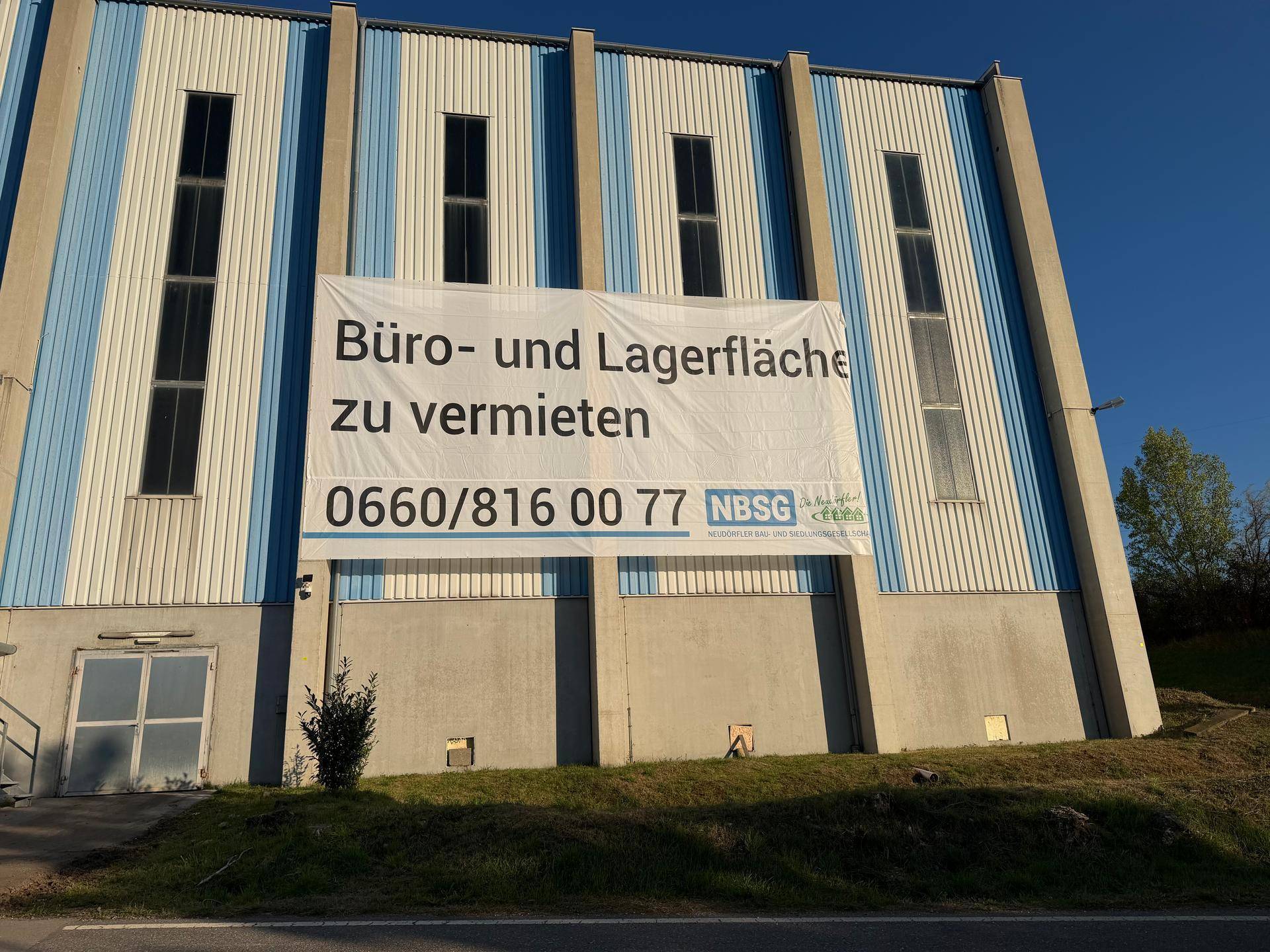 Außenansicht des Industriegebäudes mit einem großen Banner, das Büro- und Lagerflächen zur Miete anbietet.