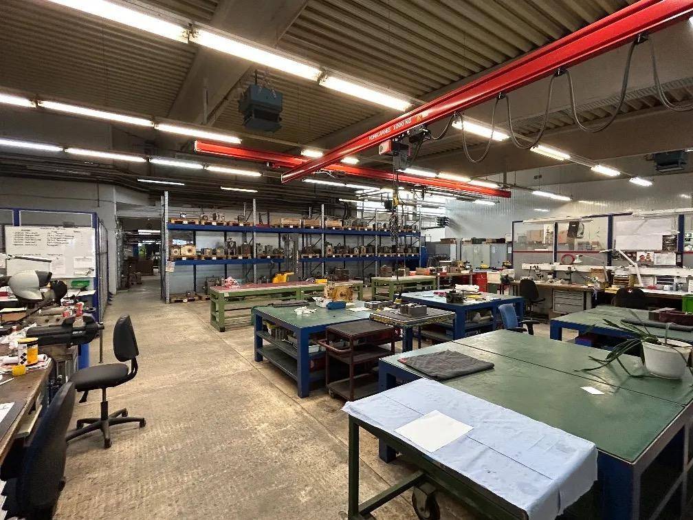 Große Werkstatt mit vielen Arbeitsplätzen, Maschinen und einem roten Kran.