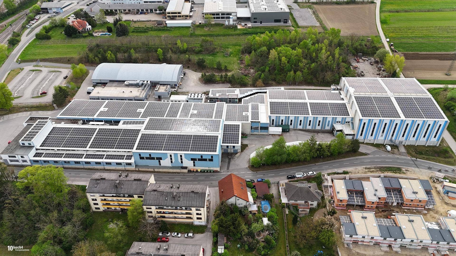 Weitläufige Luftaufnahme eines Gewerbegebiets mit mehreren Gebäuden und Photovoltaikanlagen auf den Dächern.