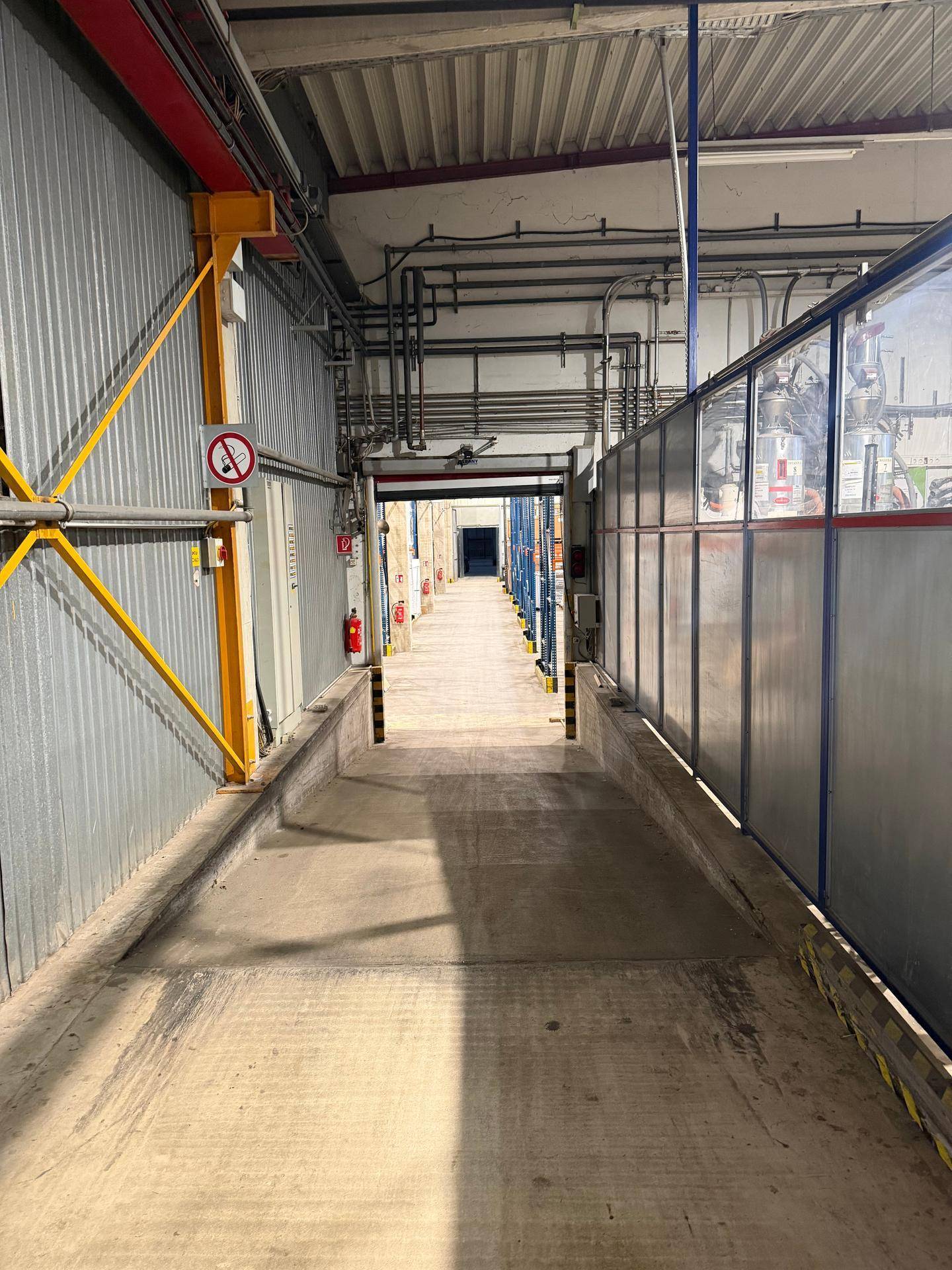 Industrieller Laderampenbereich oder Korridor mit sichtbaren Rohrleitungen und technischen Installationen an der Decke.