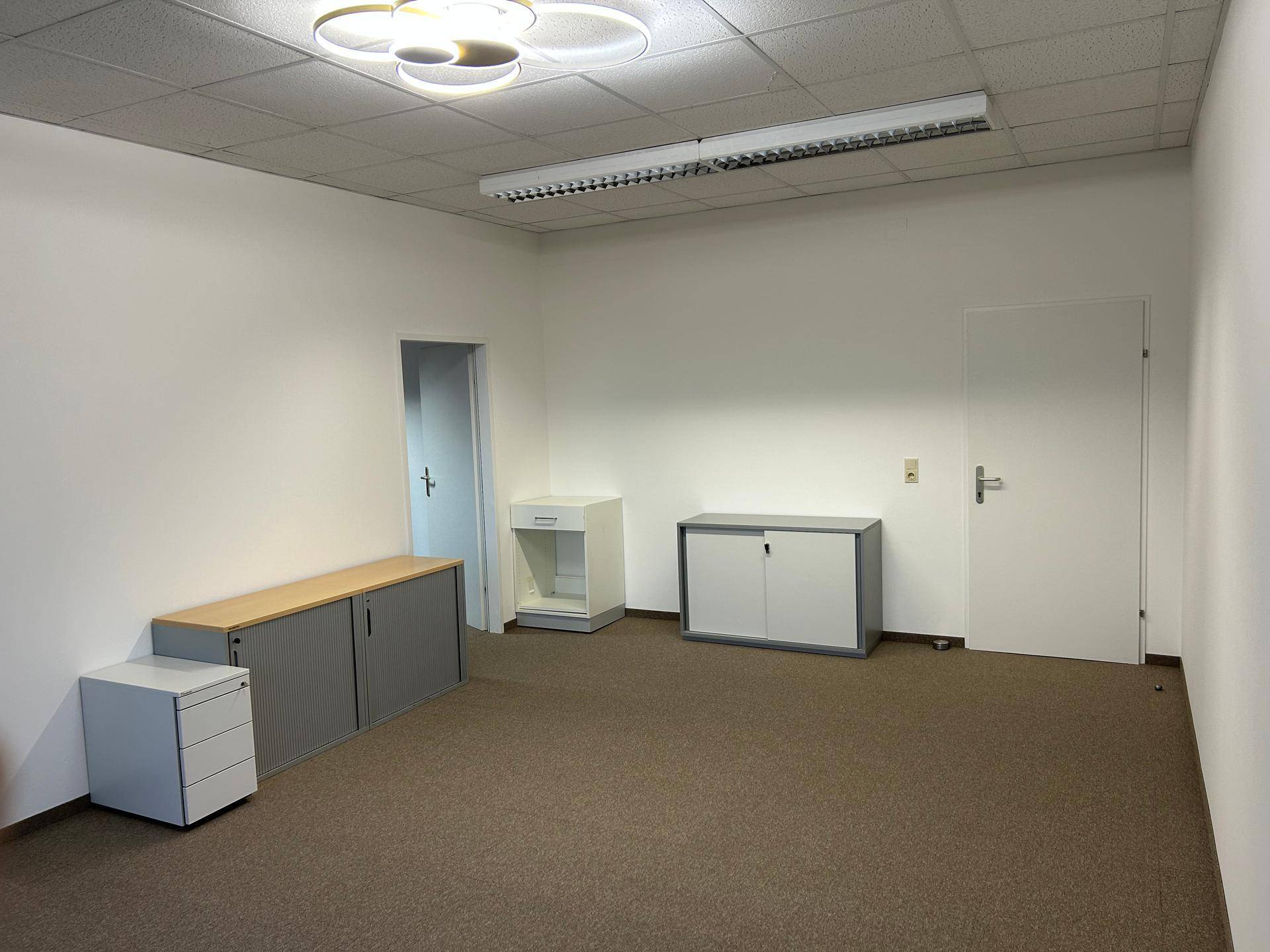 Leeres Büro mit Teppichboden und einigen Büromöbeln, bereit zur individuellen Gestaltung.