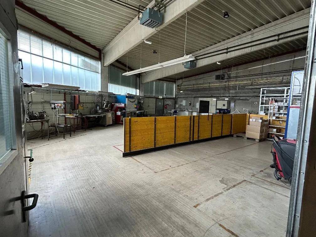 Werkstattbereich mit Arbeitsplätzen, hohen Decken und großen Fenstern für viel Tageslicht.