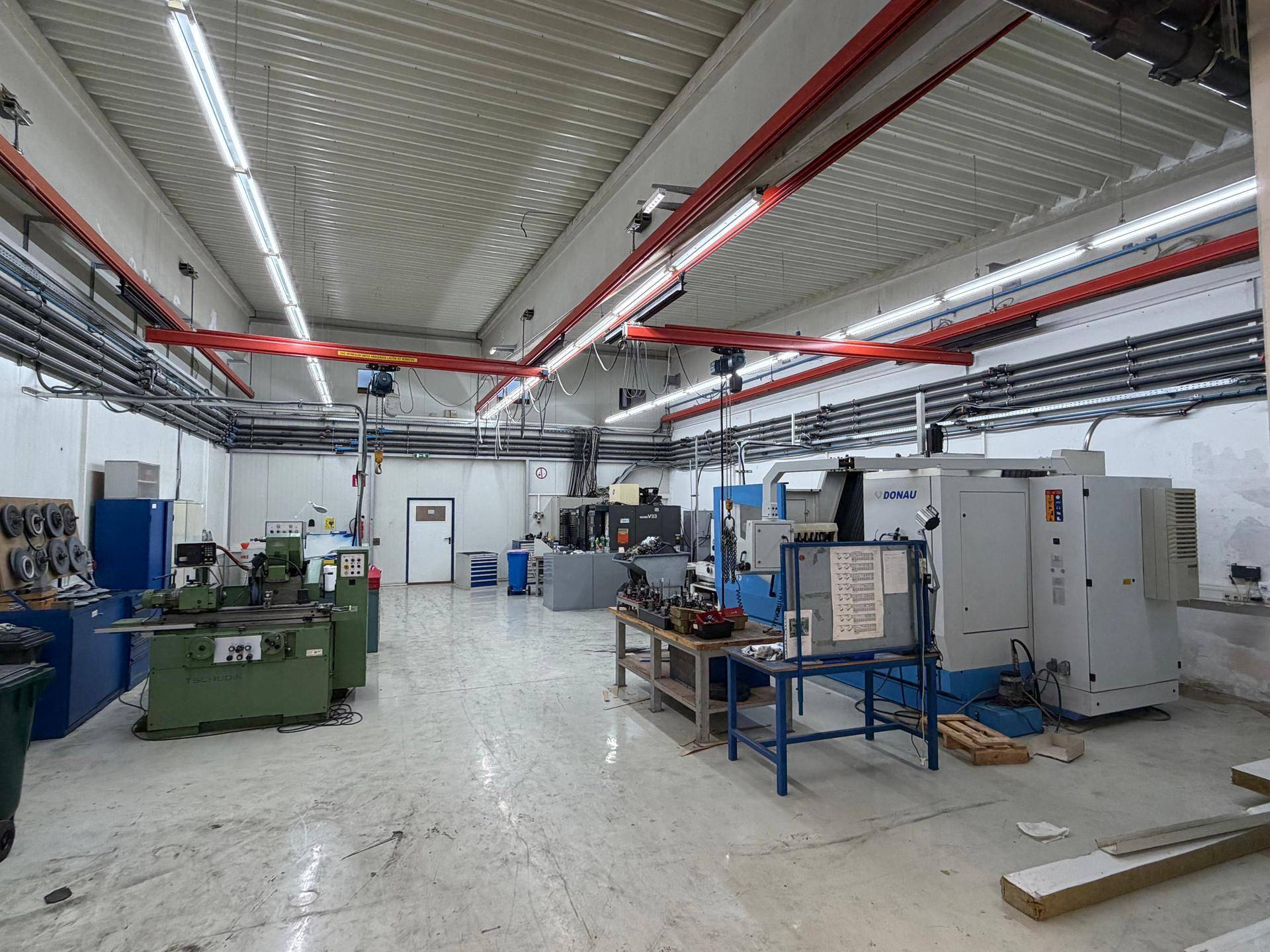 Werkstatt oder kleinerer Produktionsbereich mit verschiedenen Maschinen, Werkbänken und Arbeitsplätzen.