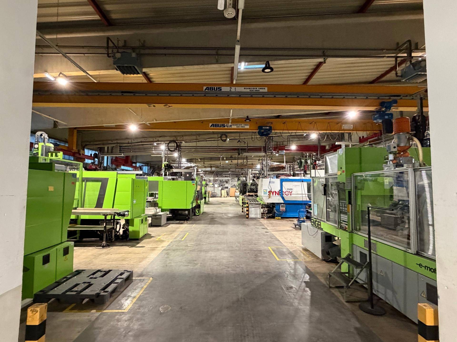 Große Produktionshalle mit zahlreichen Industriemaschinen, hohen Decken und sichtbaren Krananlagen.