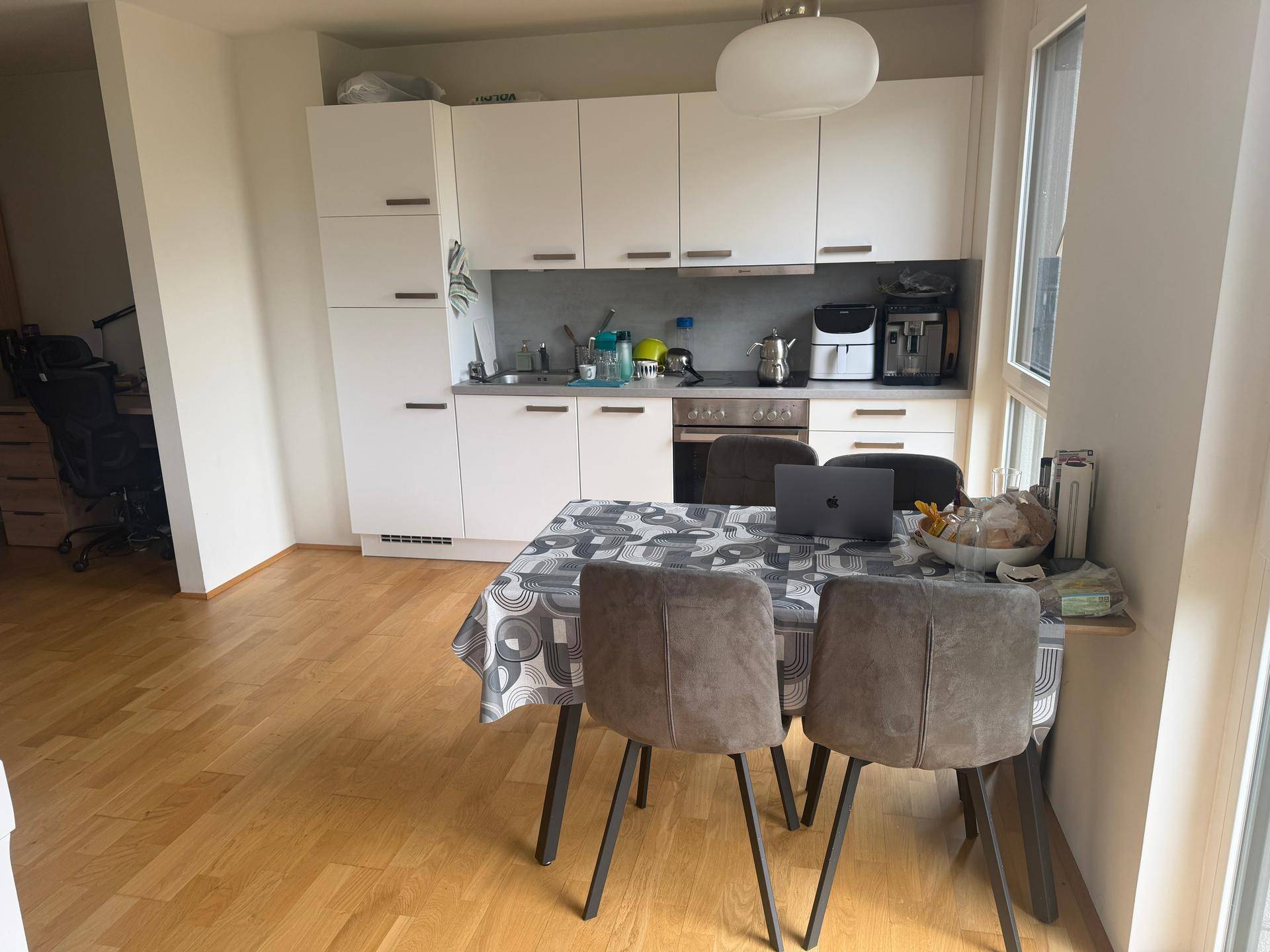Funktionale Küche mit weißen Schränken und Essbereich, ideal für gemeinsame Mahlzeiten.