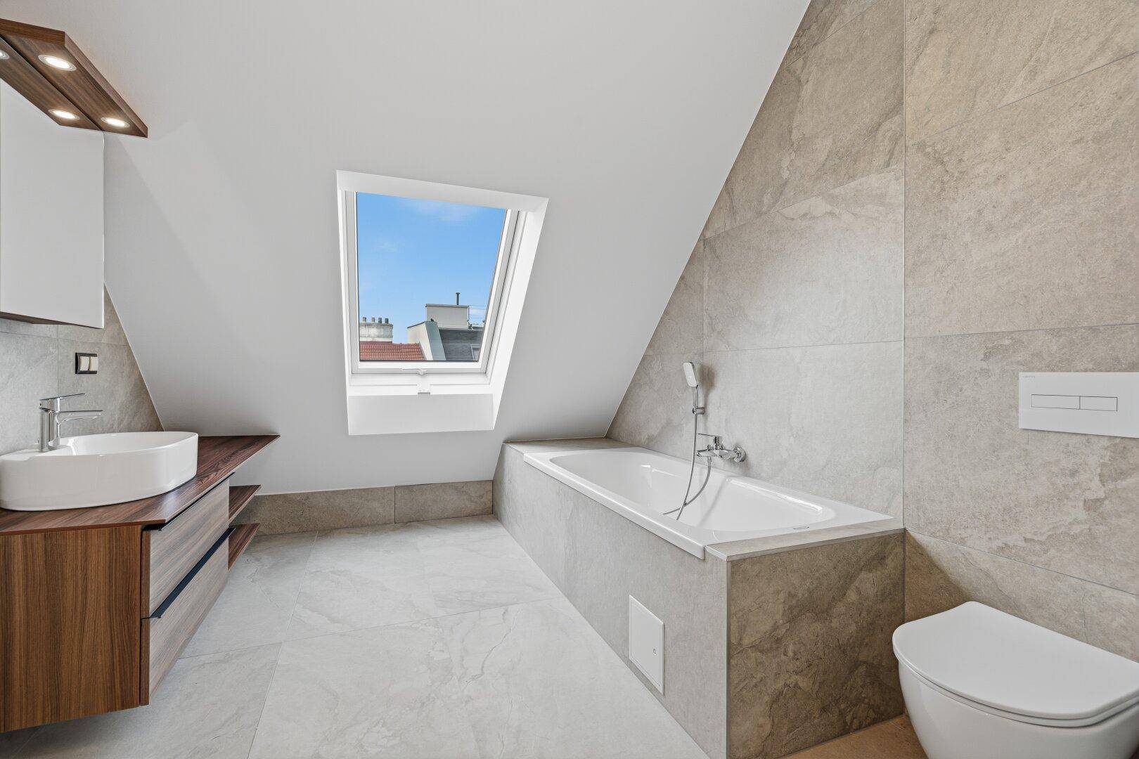 Modernes Badezimmer mit Dachfenster, Badewanne, schwebendem Waschtisch und Wand-WC.