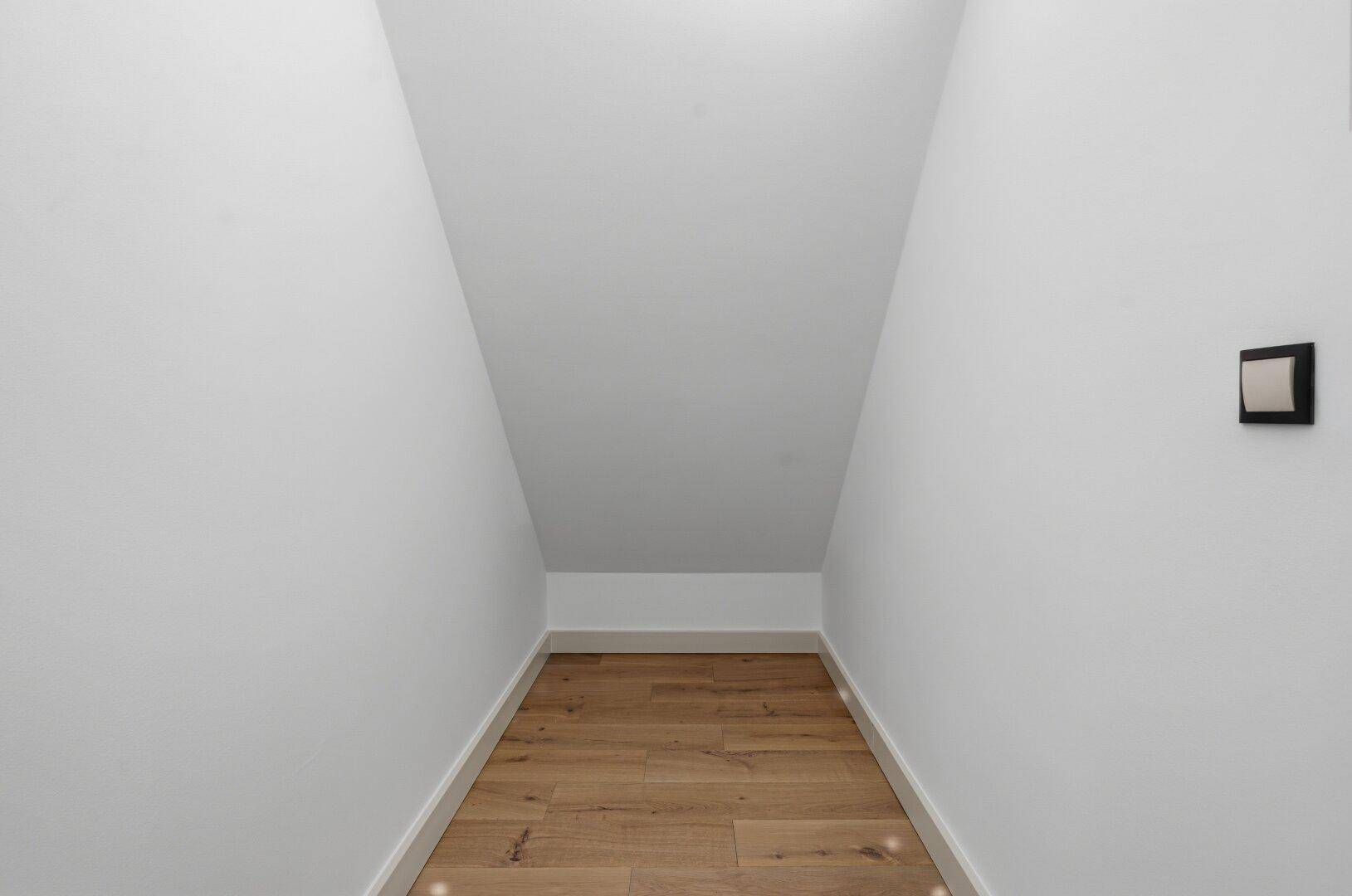 Kleiner Abstellraum mit Dachschräge und Holzboden, ideal für zusätzlichen Stauraum.