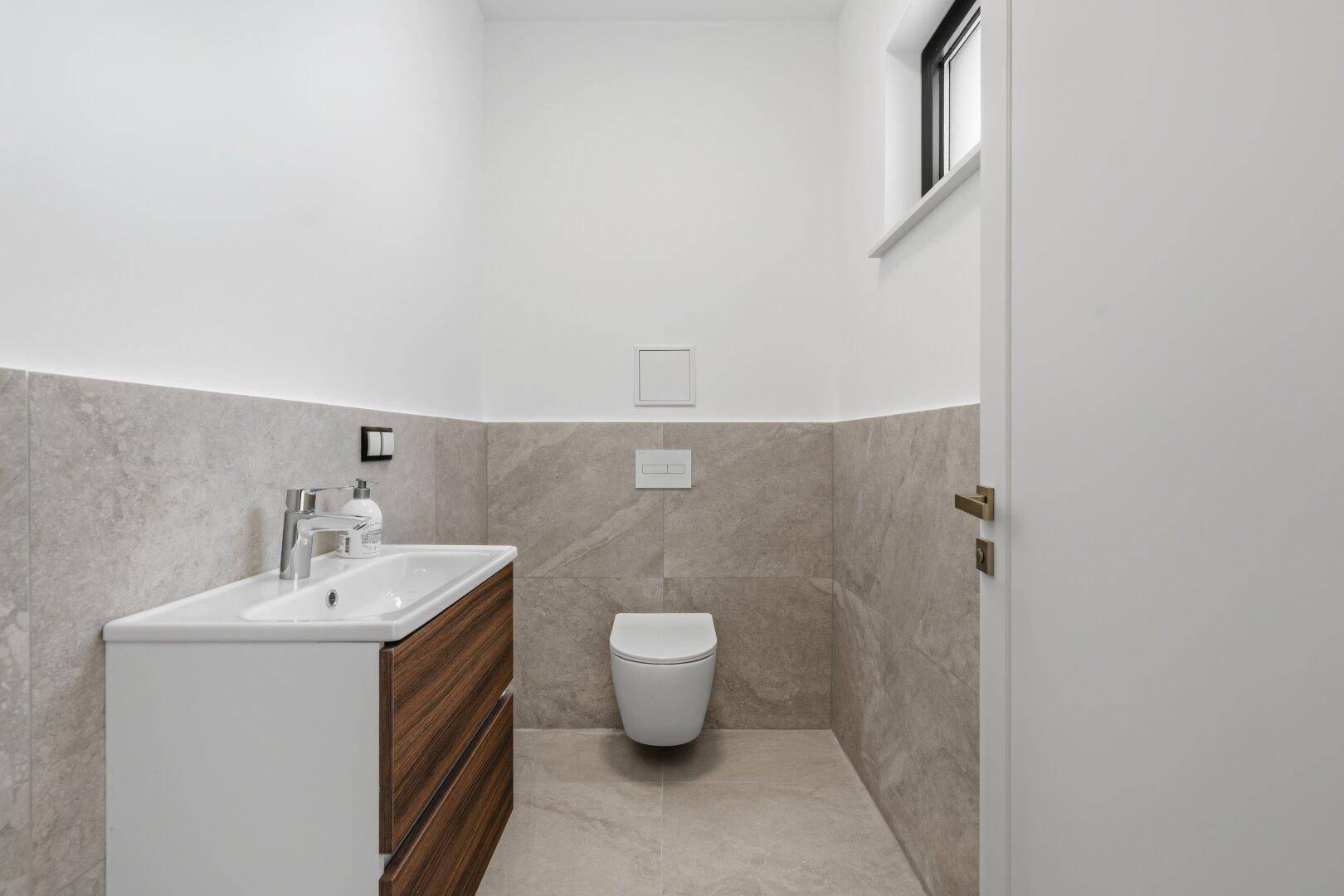 Modernes Gäste-WC mit Fenster, schwebendem Waschtisch und Wand-WC.