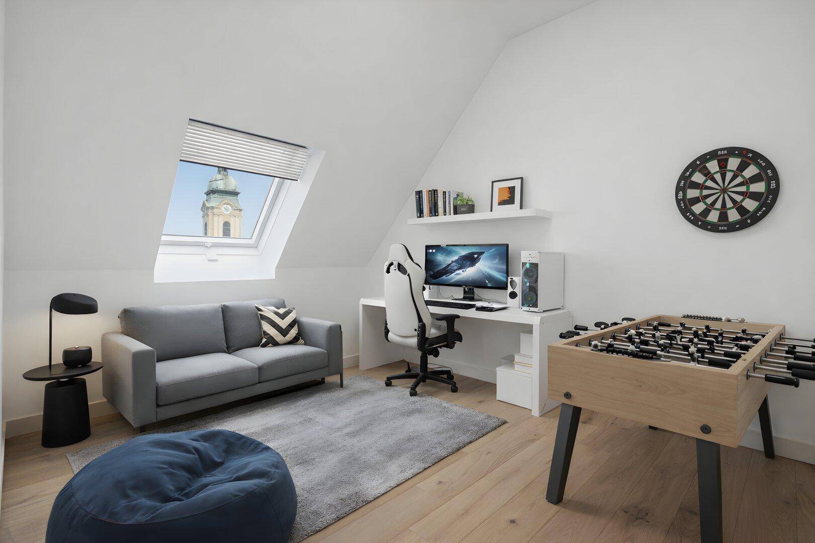 Helles Dachzimmer mit Schreibtisch, Sofa, Tischfußball und Blick auf einen Kirchturm durch das Dachfenster.