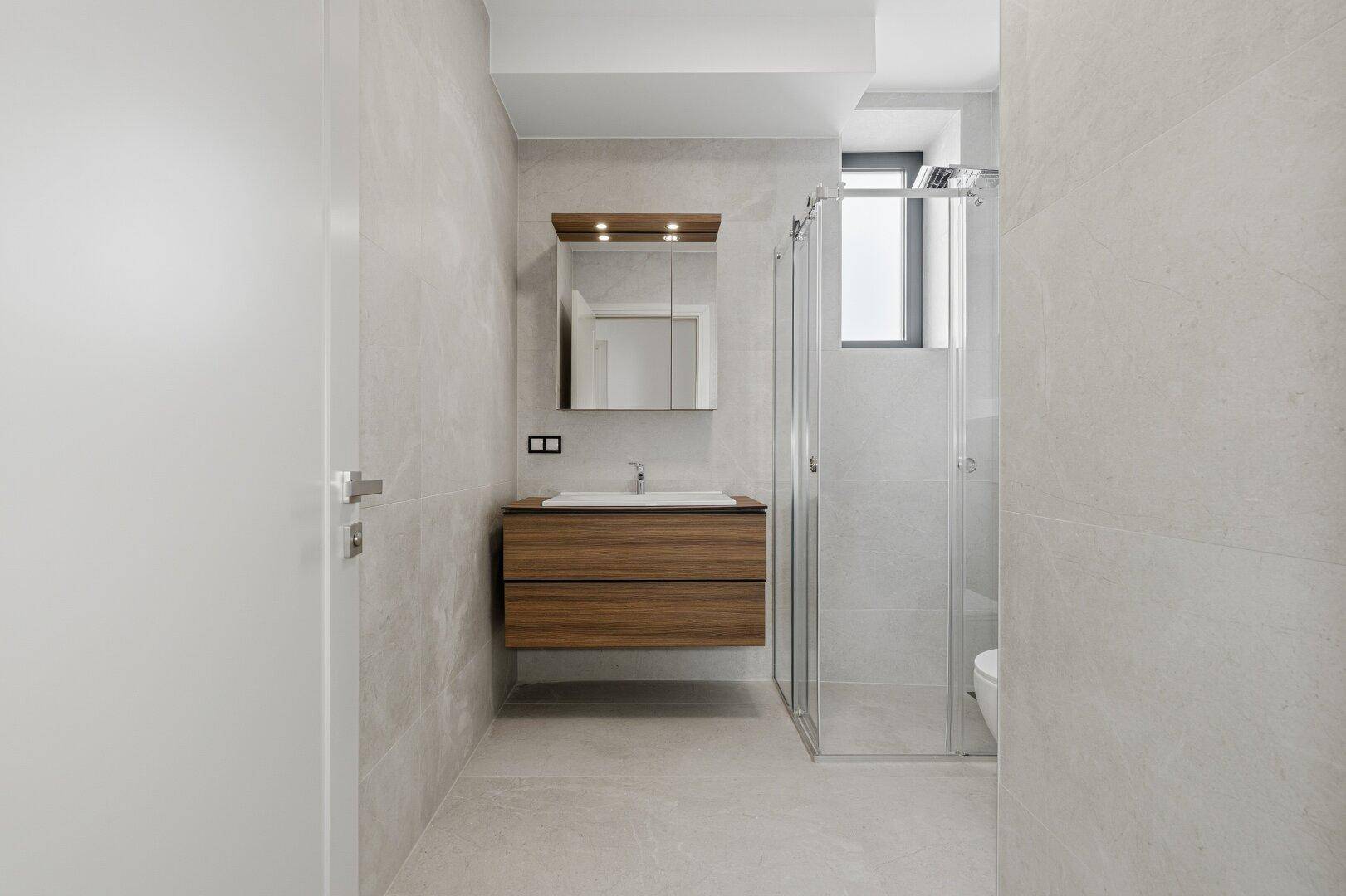 Modernes Badezimmer mit schwebendem Holzwaschtisch, Spiegelschrank und begehbarer Dusche.