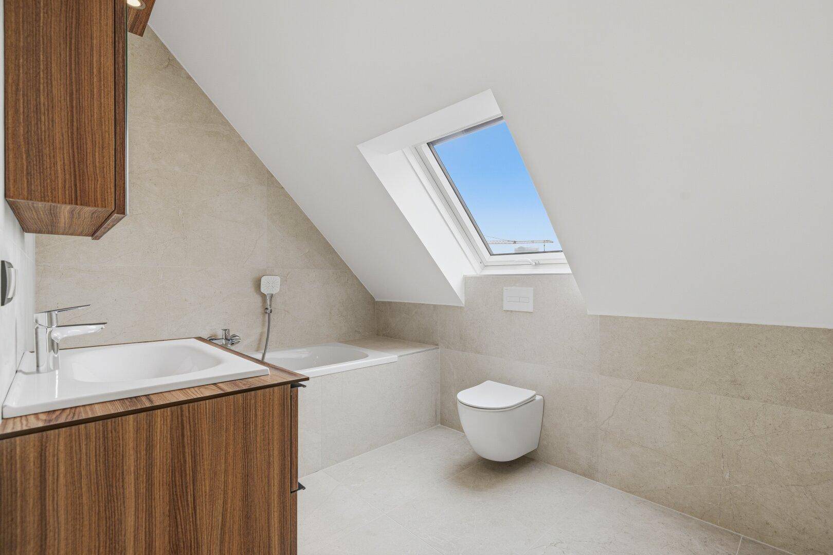 Modernes Badezimmer mit Badewanne, schwebendem Waschtisch und Dachfenster unter der Schräge.