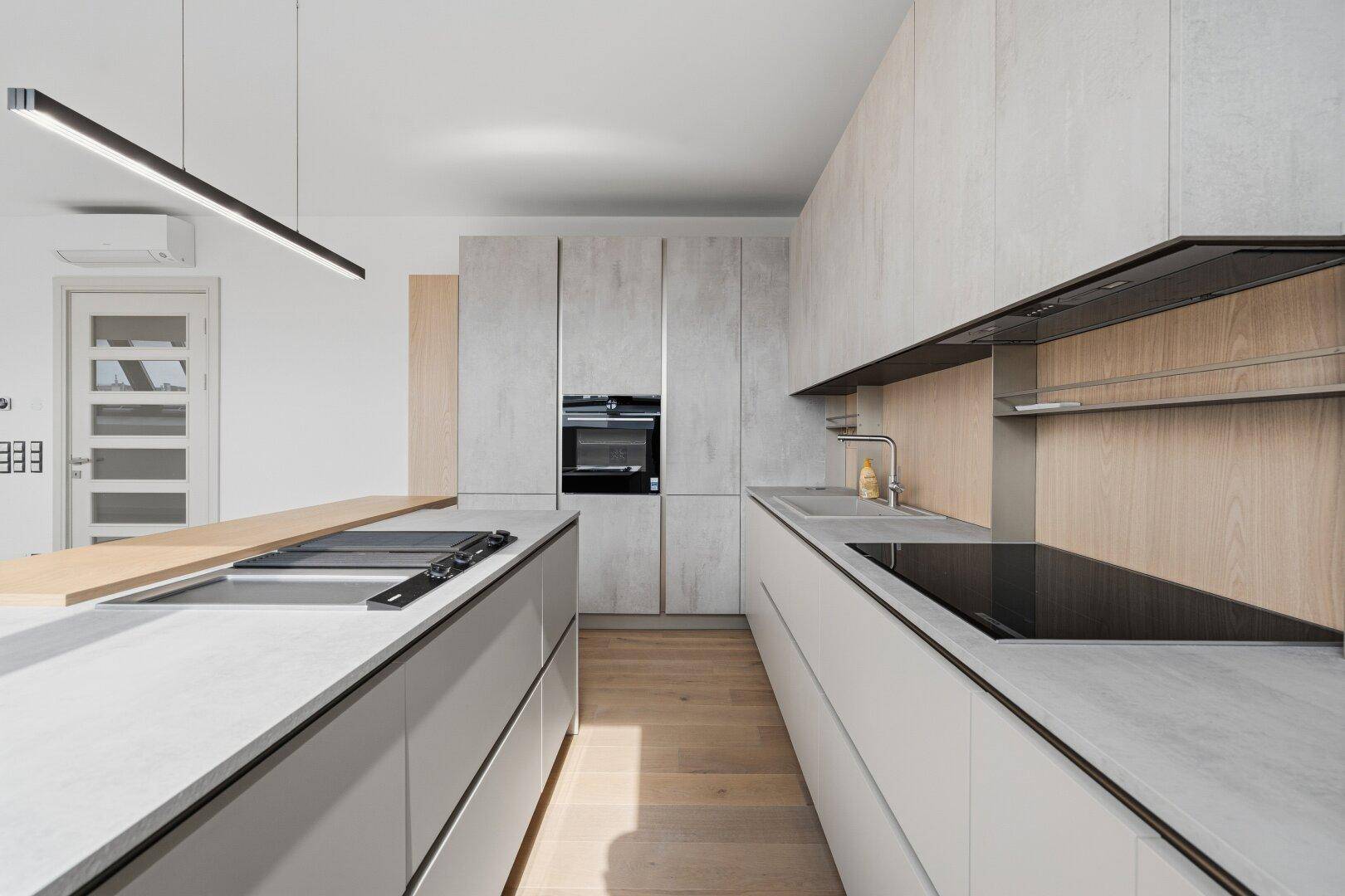 Elegante Küche mit langer Arbeitsplatte, Kochinsel und modernen Geräten, bietet viel Platz zum Kochen.