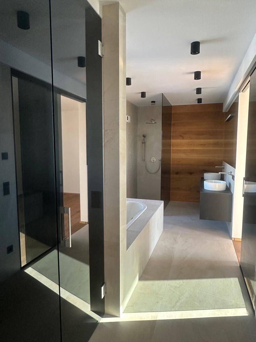 Modernes Badezimmer mit Glasdusche, Badewanne und stilvollen Holz- und Fliesenakzenten.