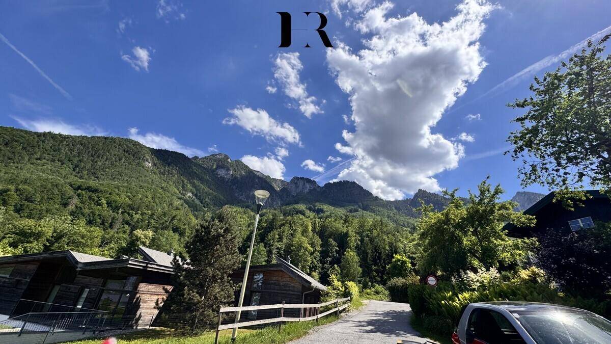 Malerische Berglandschaft mit bewaldeten Hängen, blauem Himmel und einer ländlichen Straße.