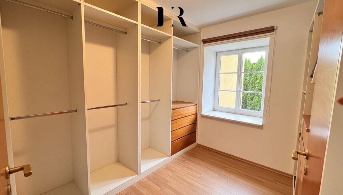 Praktischer begehbarer Kleiderschrank mit Einbauschränken und Fenster für Tageslicht.