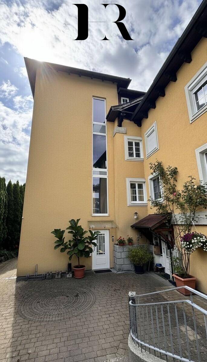 Attraktive gelbe Fassade des Gebäudes mit hohen Fenstern und gepflastertem Eingangsbereich.