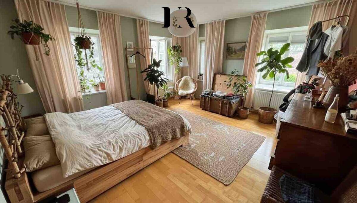 Gemütliches Schlafzimmer mit Holzbett, Parkettboden und vielen Pflanzen, das zum Wohlfühlen einlädt.