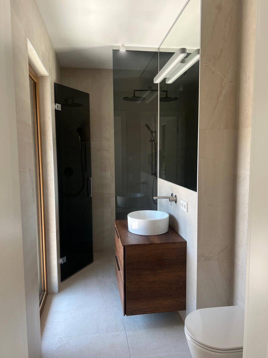 Kompaktes Badezimmer mit modernem Waschbecken, Toilette und Duschbereich mit Fenster.