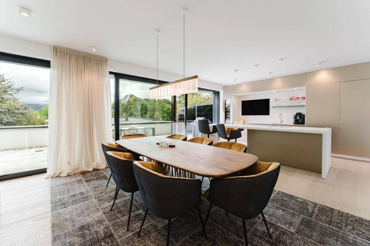 Eleganter Essbereich mit großem Holztisch, modernen Stühlen und Zugang zur Terrasse.