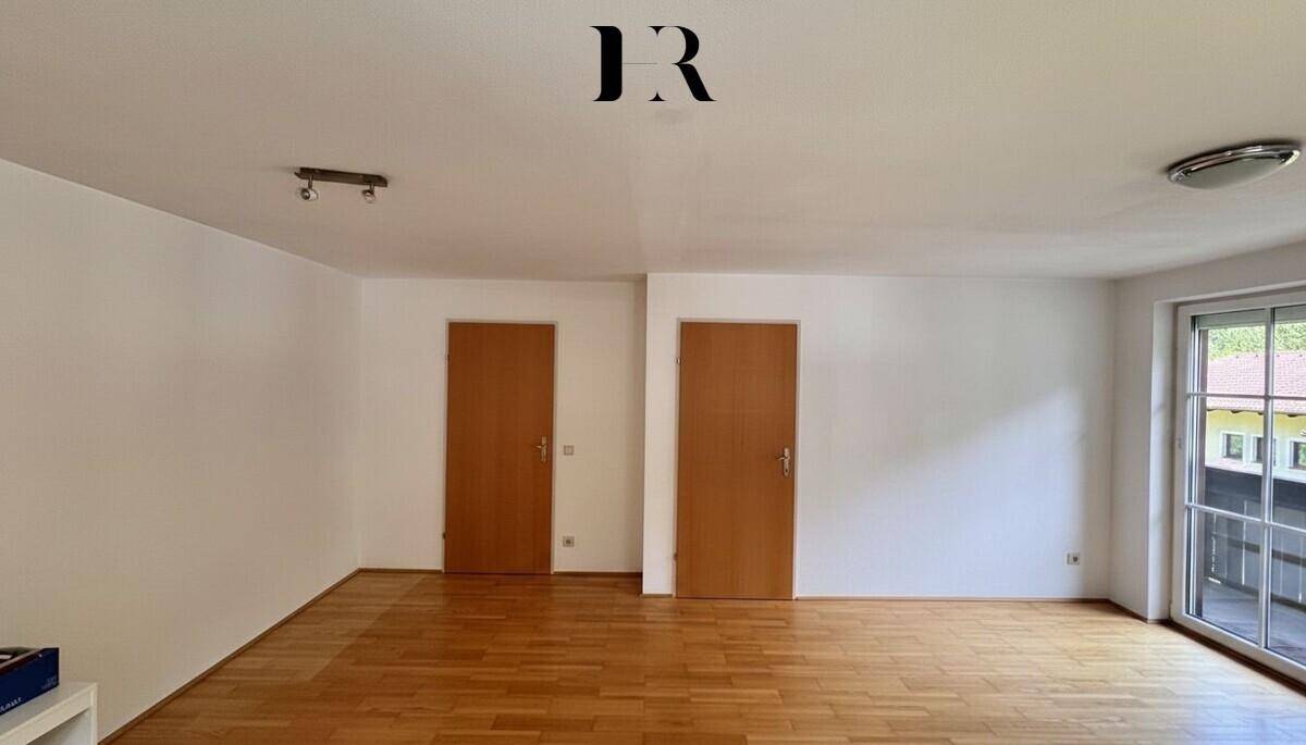 Geräumiges Wohnzimmer mit Holztüren und Zugang zu einem Außenbereich, ideal für individuelle Gestaltung.