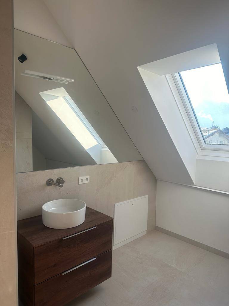 Modernes Badezimmer mit Dachfenster, schwebendem Waschtisch und großem Spiegel.