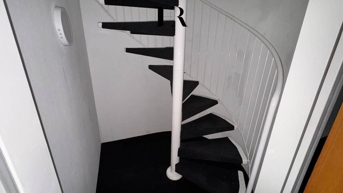 Wendeltreppe mit dunklen Stufen und weißem Geländer in einem hellen Treppenhaus.