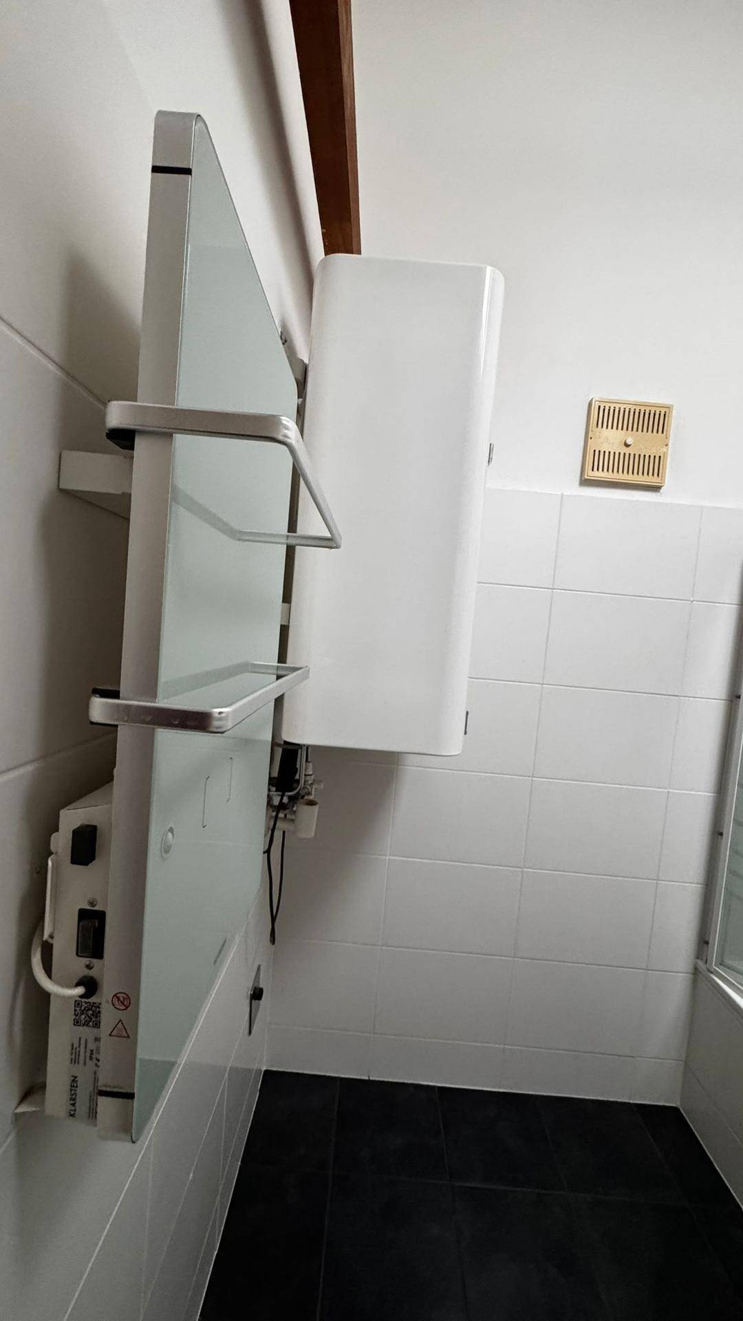 Detailansicht eines beheizten Handtuchhalters und eines Wandheizkörpers in einem gefliesten Badezimmer.