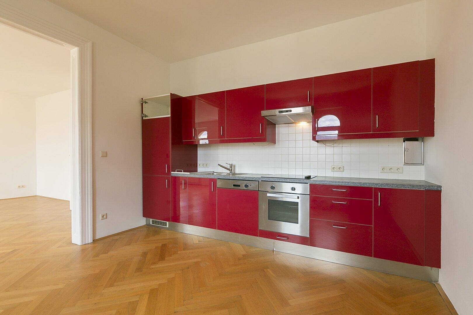 Moderne Einbauküche in leuchtendem Rot mit integrierten Geräten und viel Stauraum.